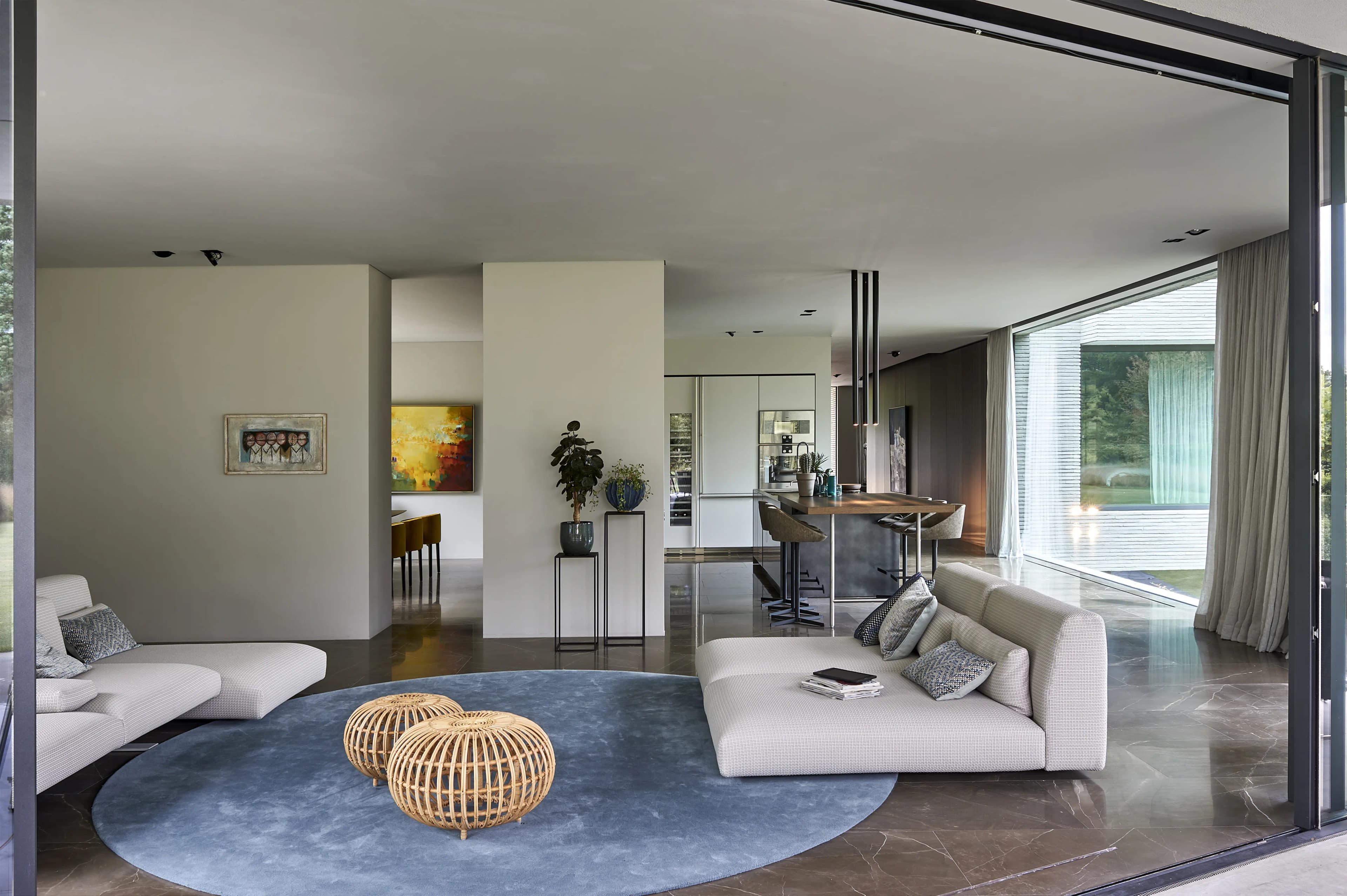 Loft-achtig interieur met wit zitmeubel, blauw tapijt en stalen balken