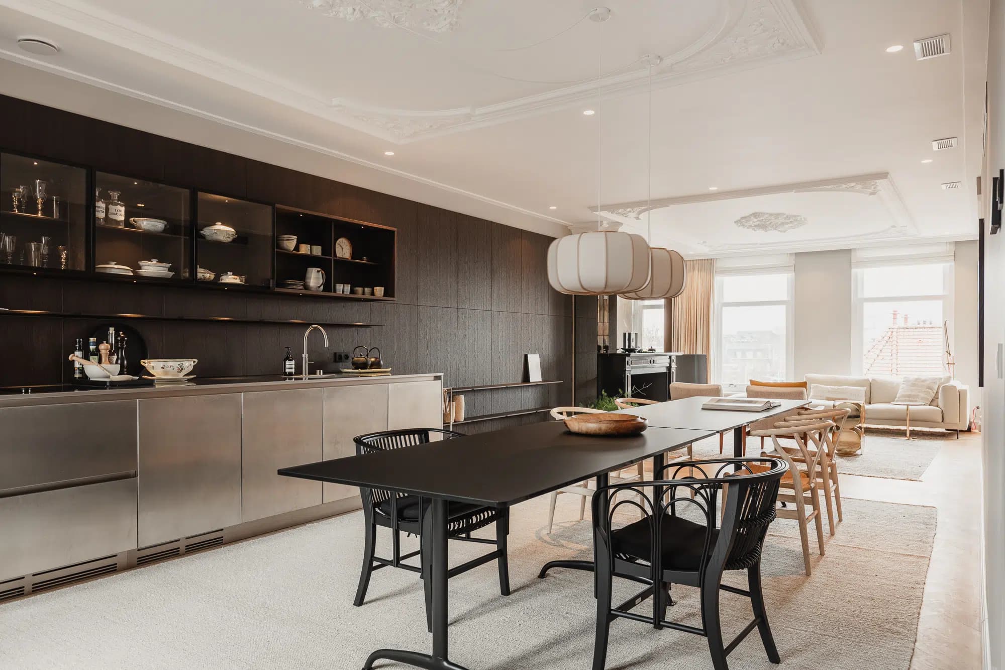 Woonkamer met beige stoffen zitmeubels, houten armstoel en grijs tapijt