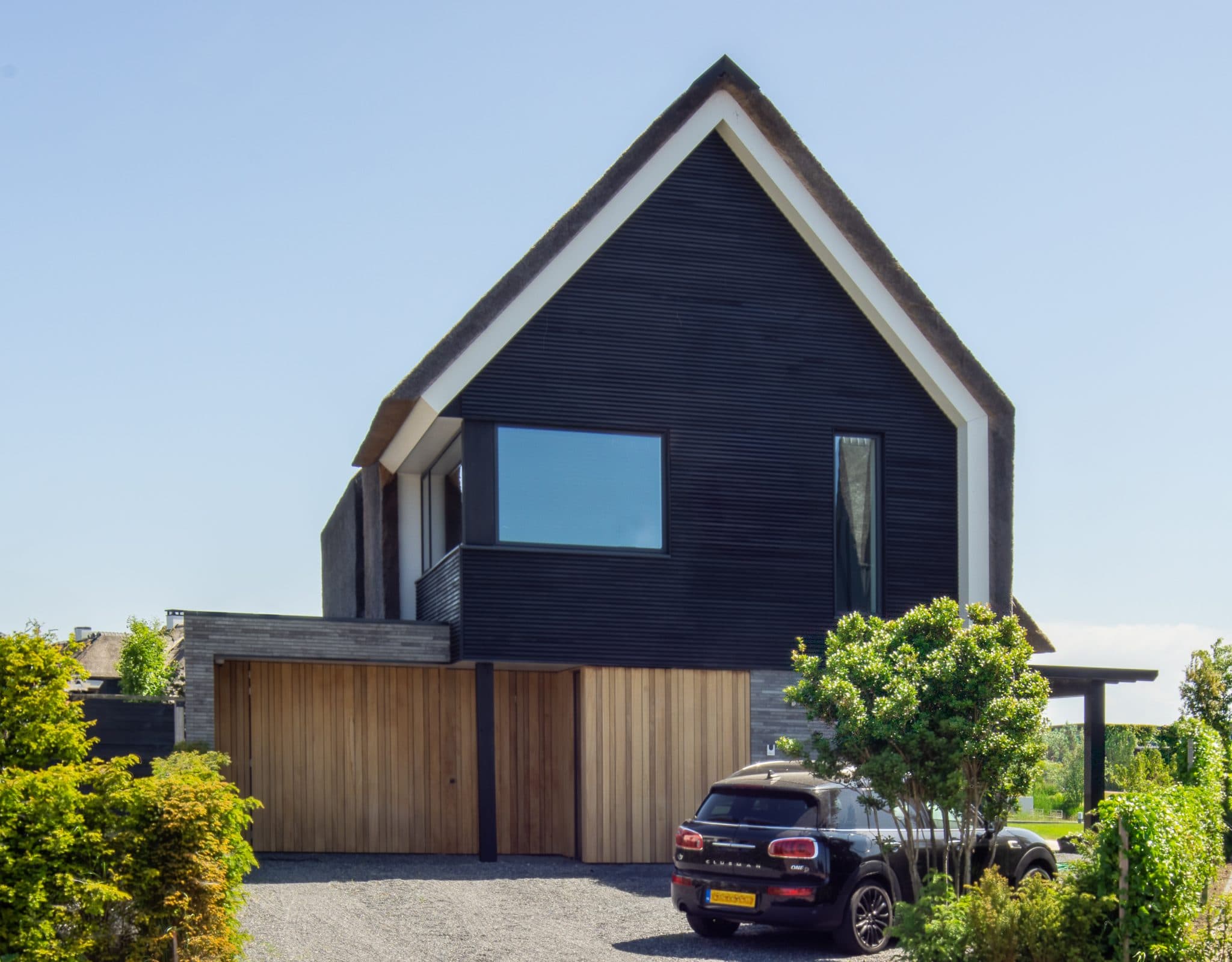 Moderne zwart-bruine villa met spitse dak, grote raam en houten deur