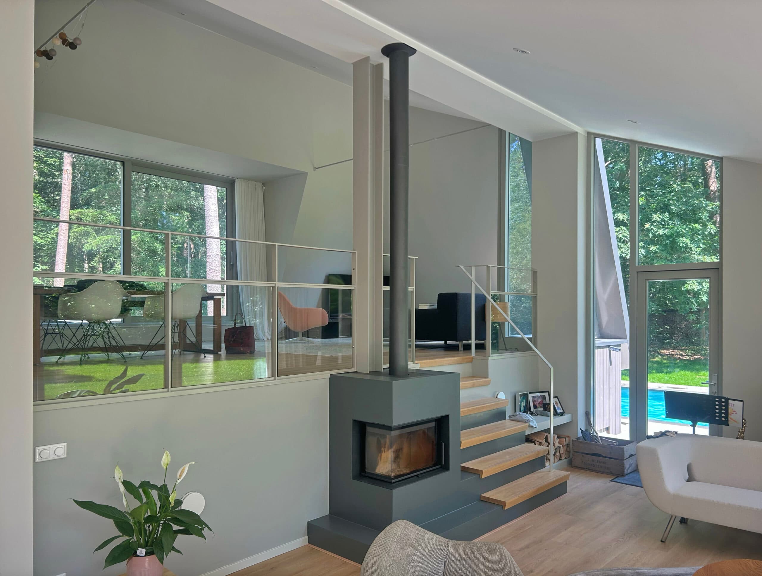 Woonkamer met zwarte gashaard, glazen wanden, houten vloer
