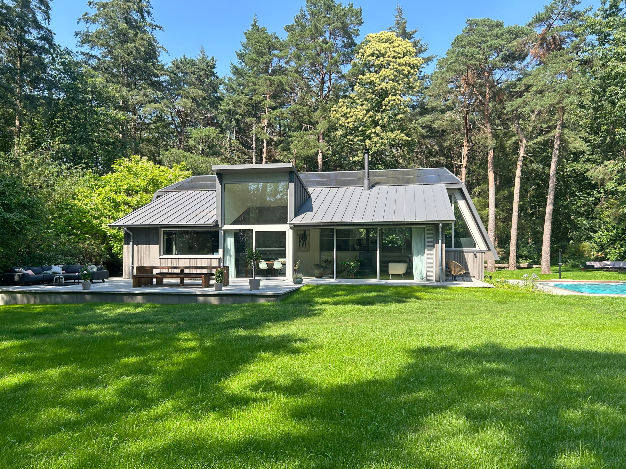 Exterieur witte villa met metalen dak, grote ramen, zwembad