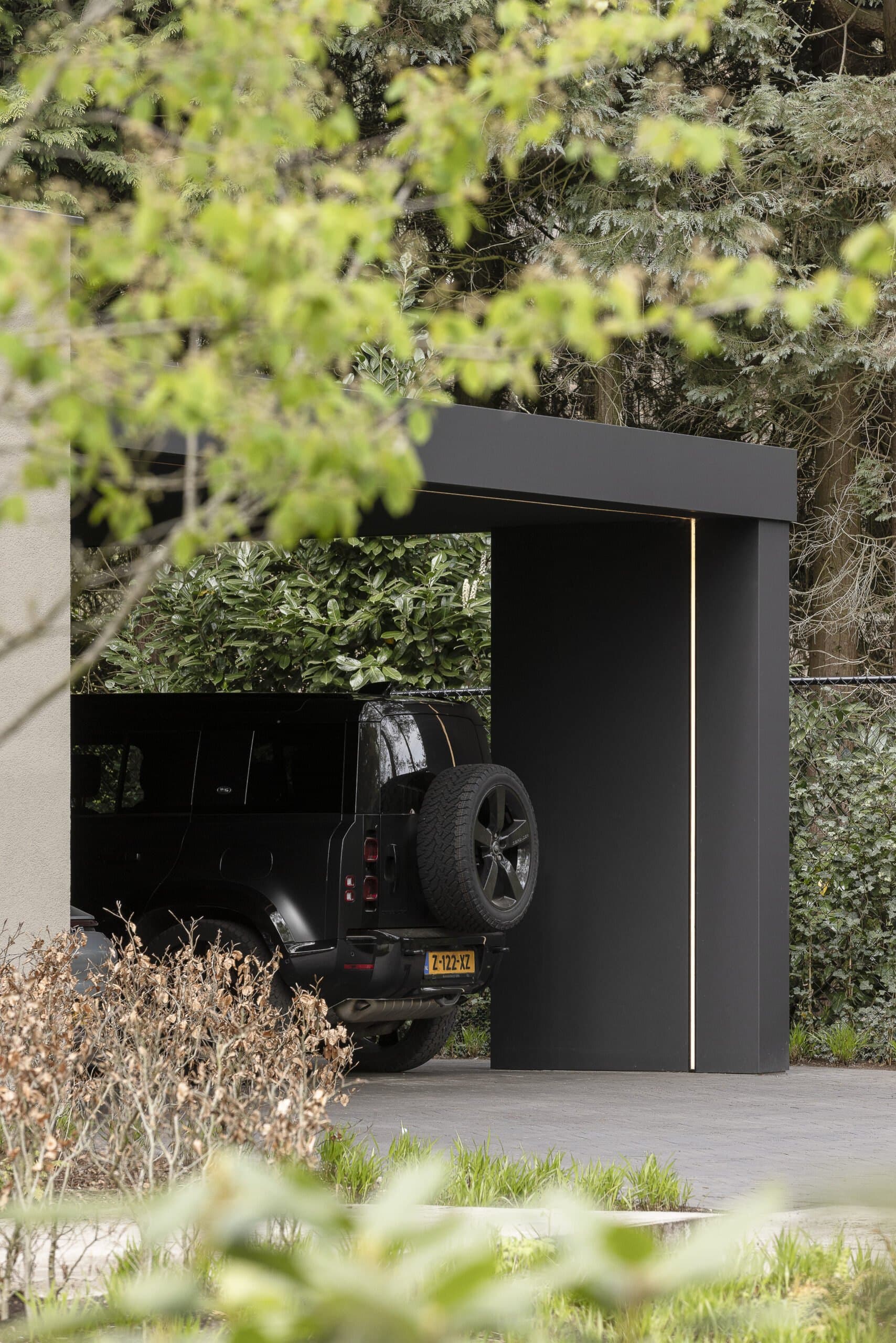 Moderne carport met zwarte stalen constructie en donkere poort