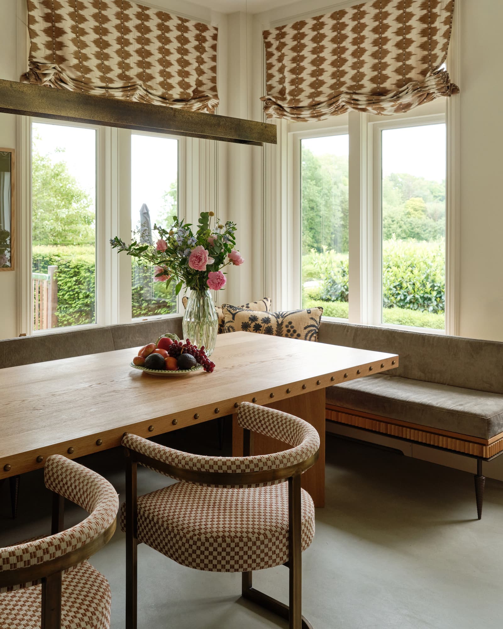 Eethoek met raambank, ruitpatroon gordijnen en houten stoelen