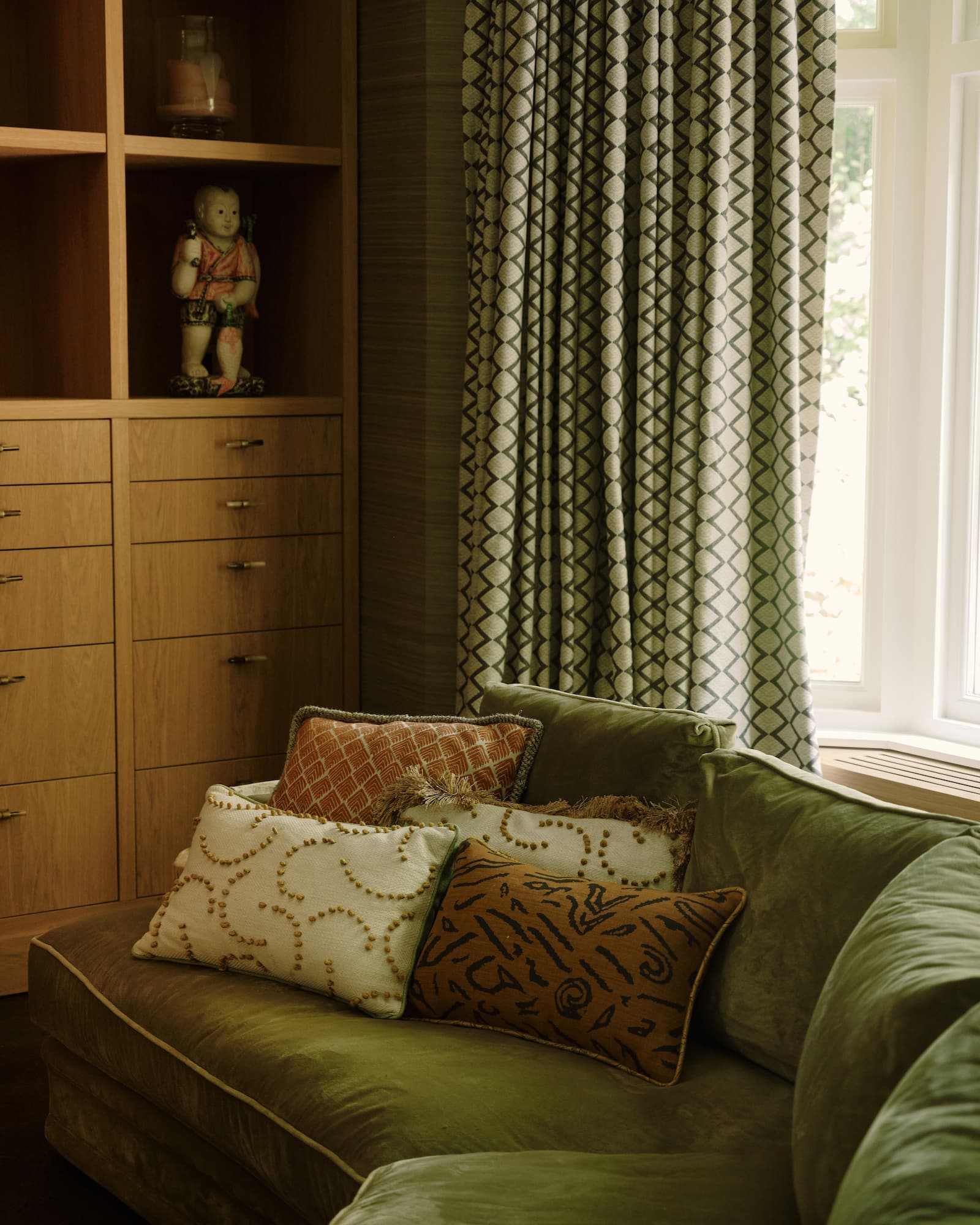 Groene sofa met decoratieve kussens en houten opslagkast