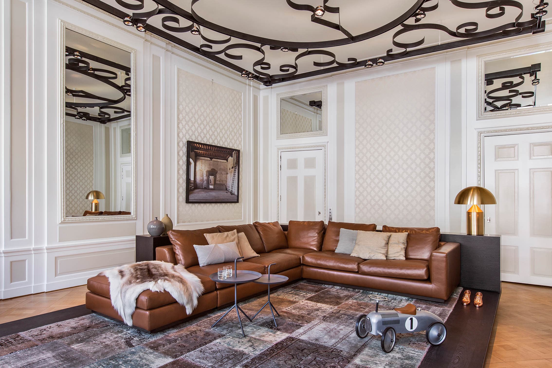 Woonkamer met cognackleurige leren hoekbank en decoratief zwart plafond met sierlijsten