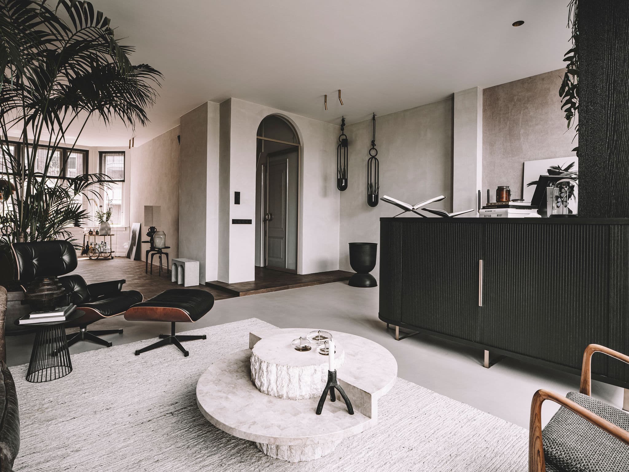 Minimalistisch interieur met houten eettafel, hangende bol-lamp en betonnen muur
