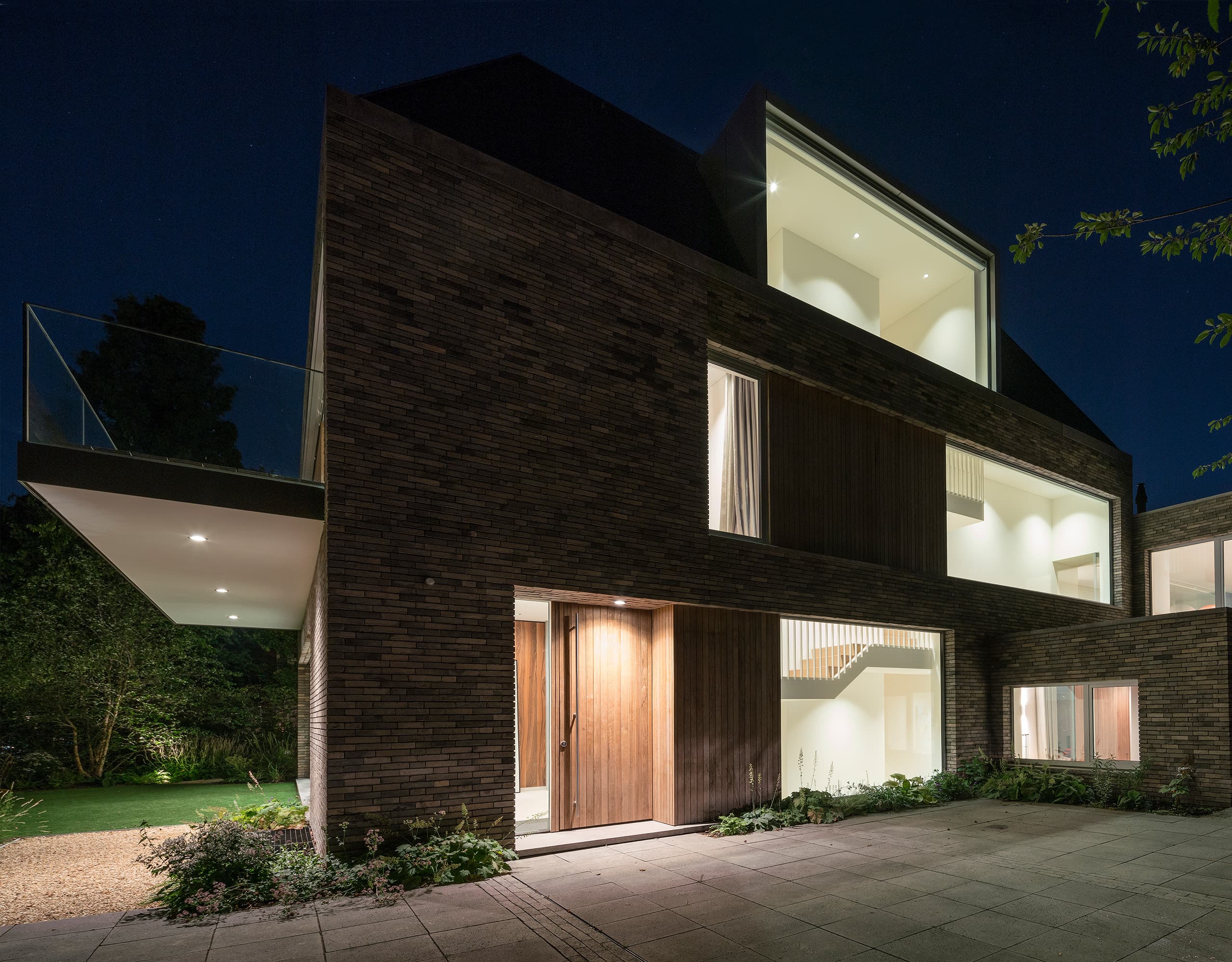 Eigentijdse villa tussen pijnbomen met zwart baksteenwerk en glazen puien