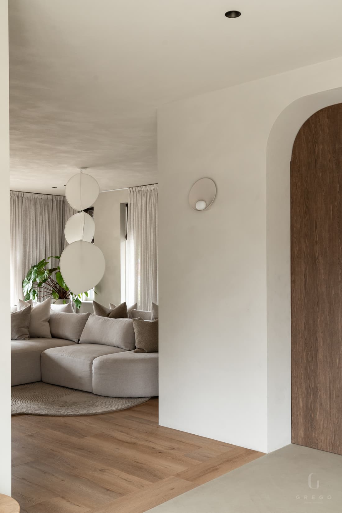 Woonkamer met beige ronde bank en hangende bollamp