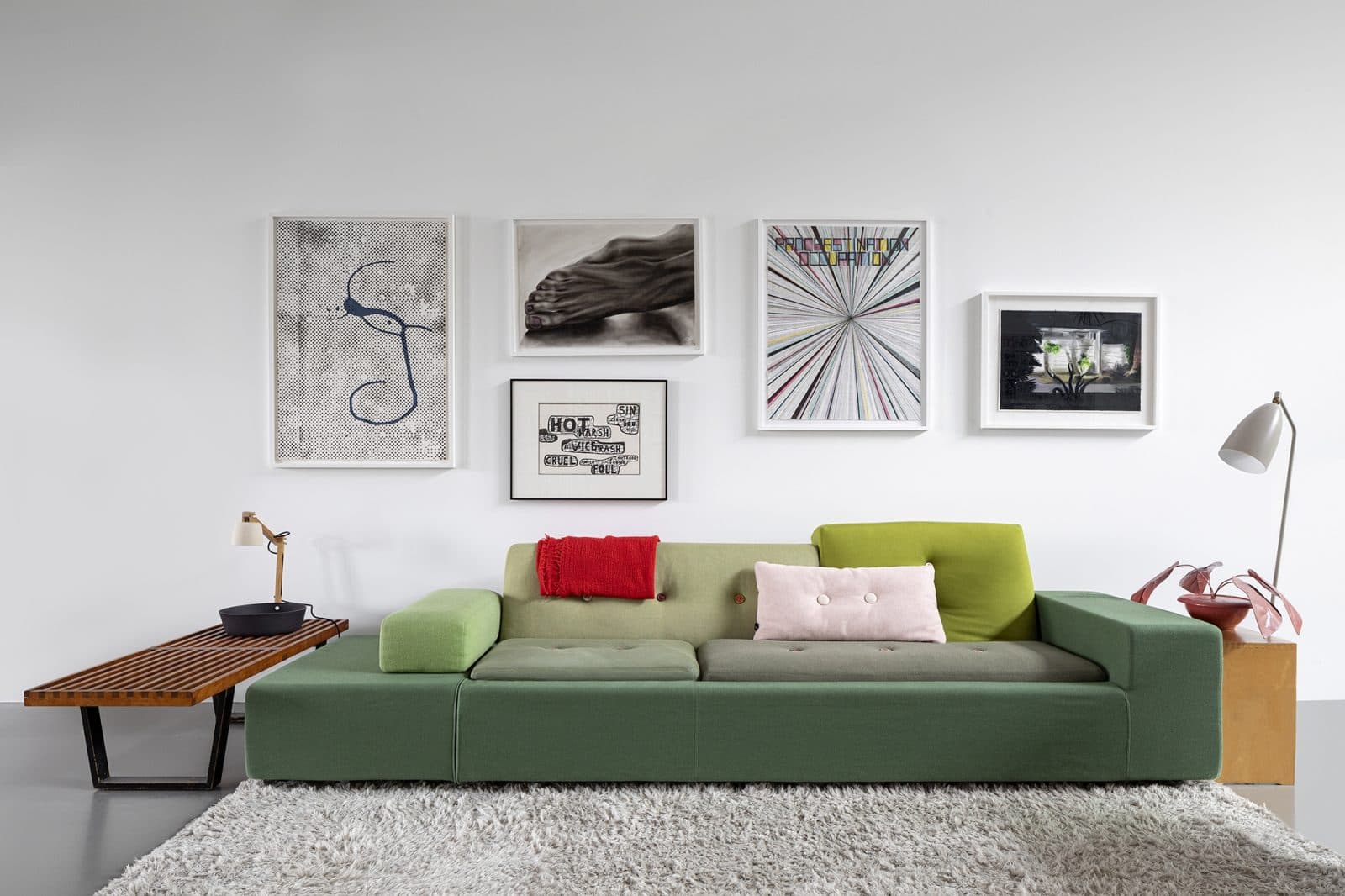 Woonkamer met groen zitmeubel en kunstwerken aan wand