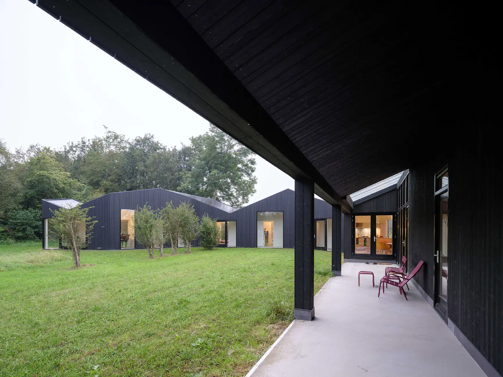 Overdekt terras zwart huis met betonnen vloer en uitzicht op weide