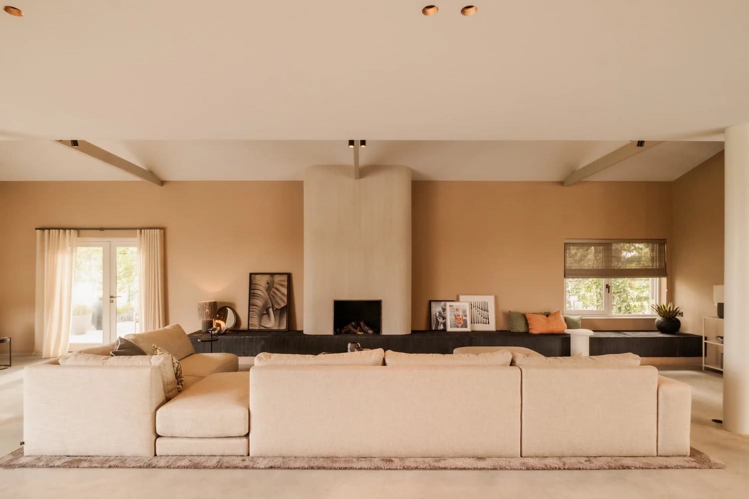 Woonkamer met beige modular sofa en zwarte haard, eiken vloer