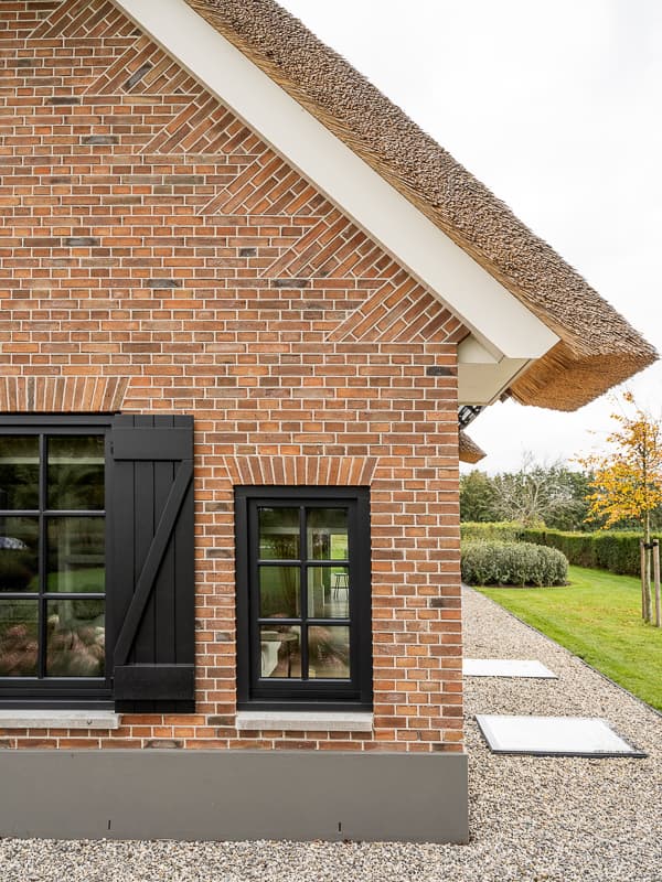 Zwarte houten kapel met spits dak en grind voortuin