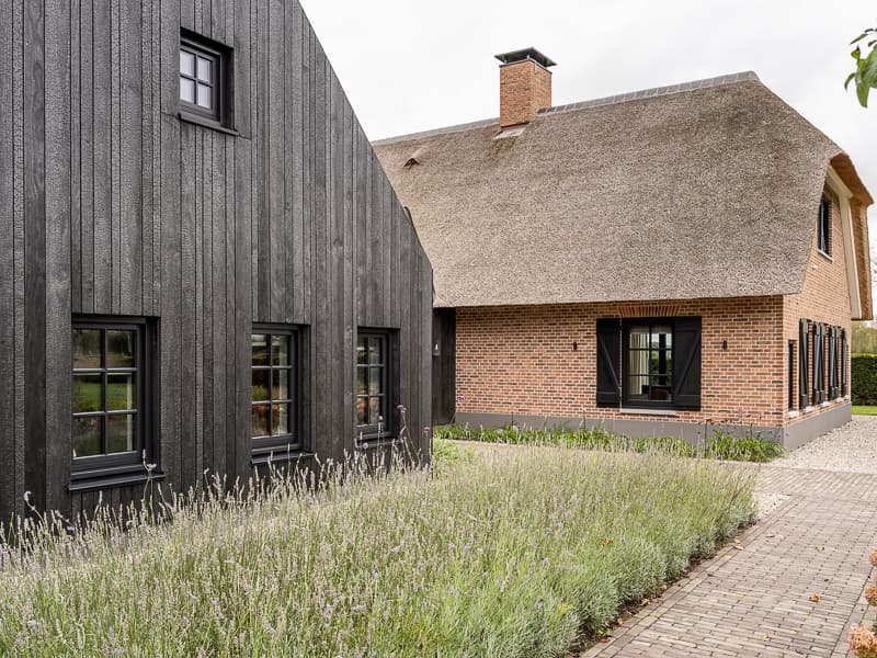 Rietgedekte boerderij met zwarte moderne uitbouw en tuin