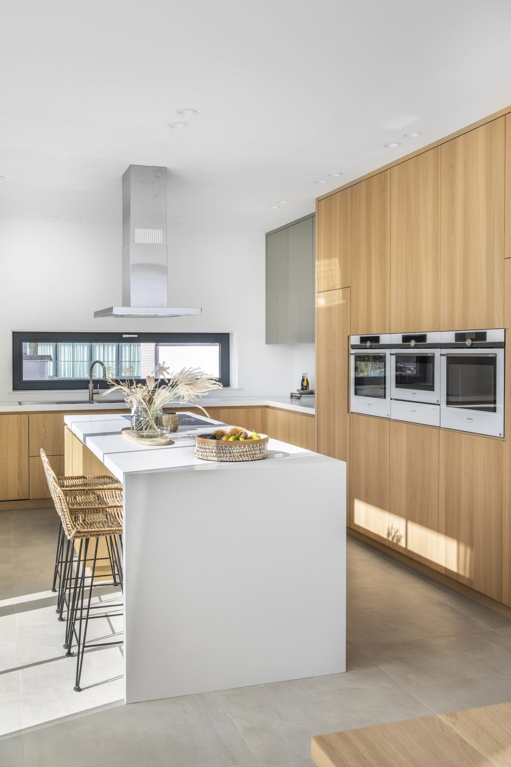 Moderne keuken met natuurlijk eiken kasten, wit eiland en roestvrijstalen inbouwapparatuur