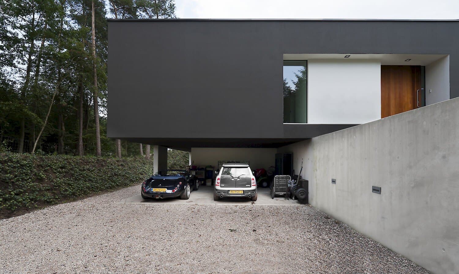 Carport onder villa met twee auto's en betonnen wanden