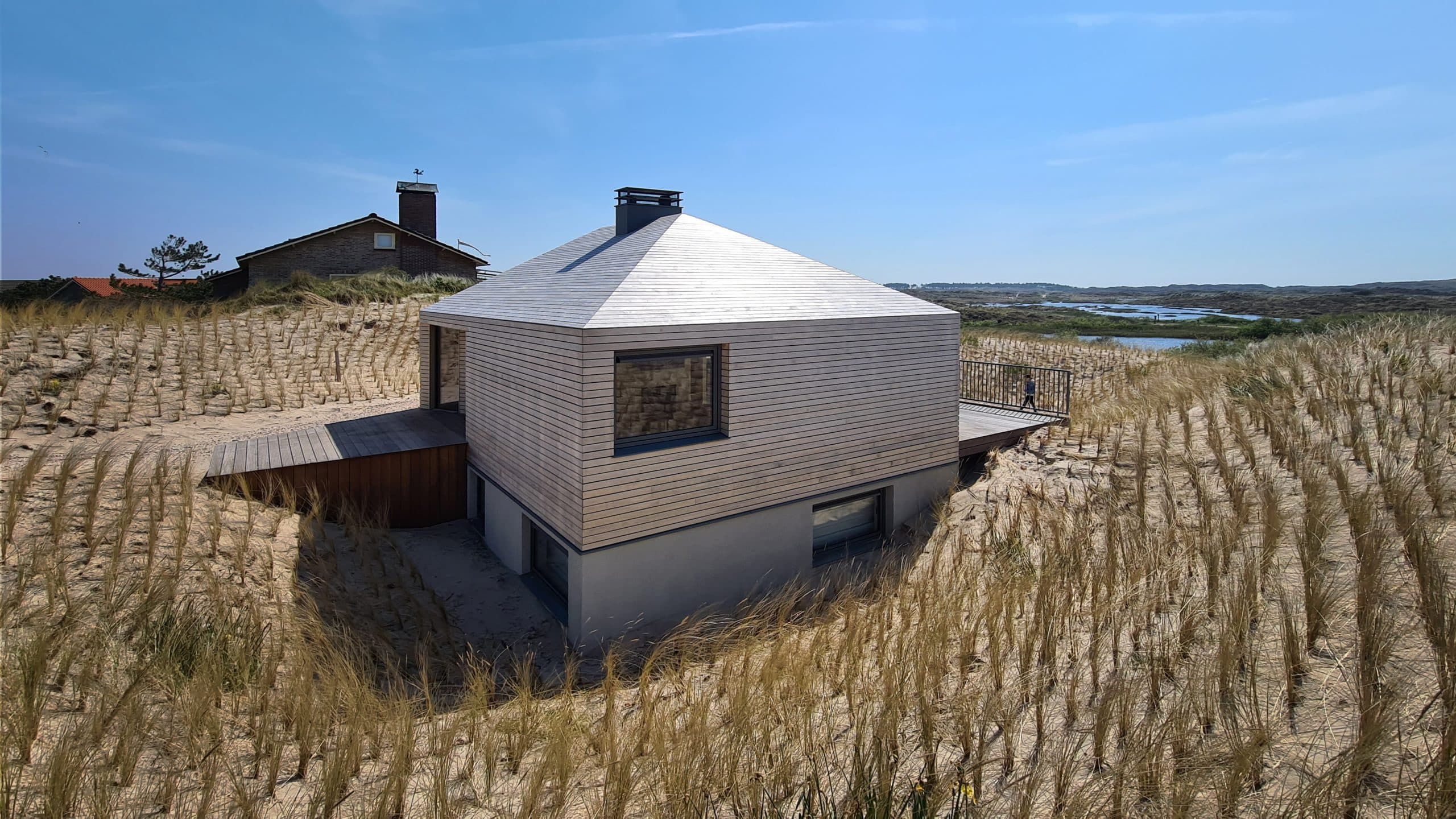 Minimalistische villa met conisch dak en grijze houten beplating in duinen