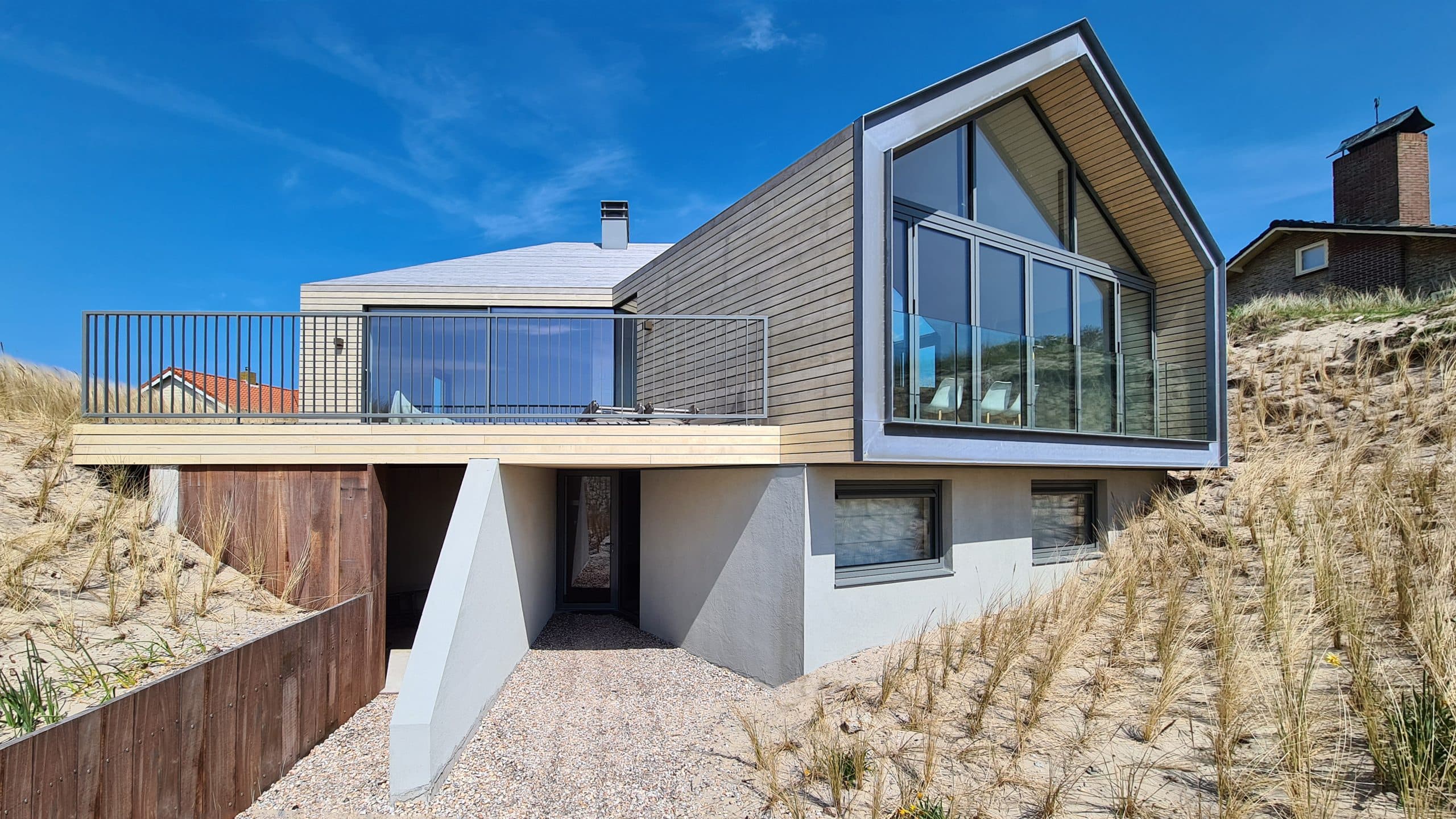 Moderne villa met grijze houten gevelbekleding en witte betonnen onderbouw