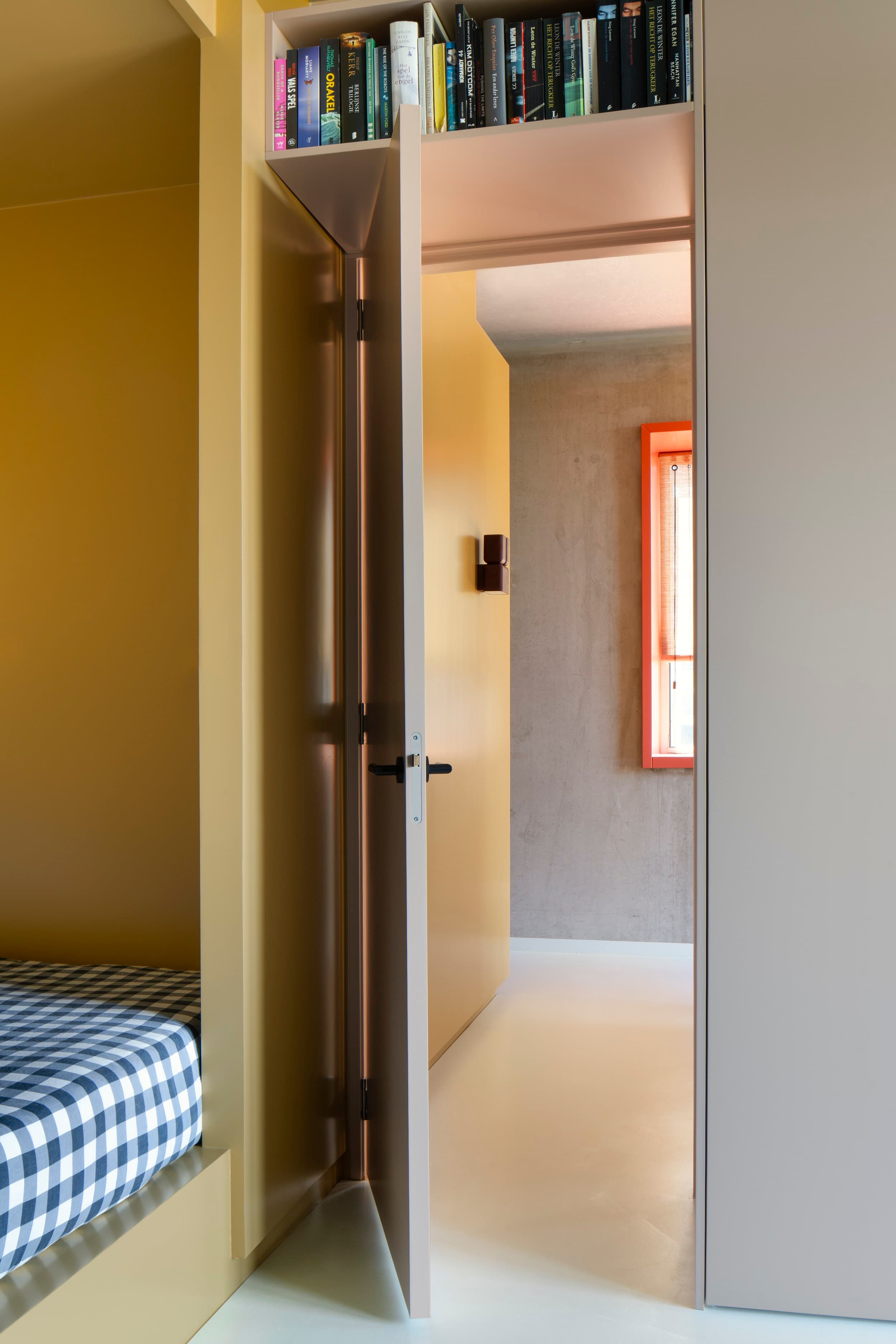 Inbouwkast met boeken, gele interieurverlichting en blauwe deur