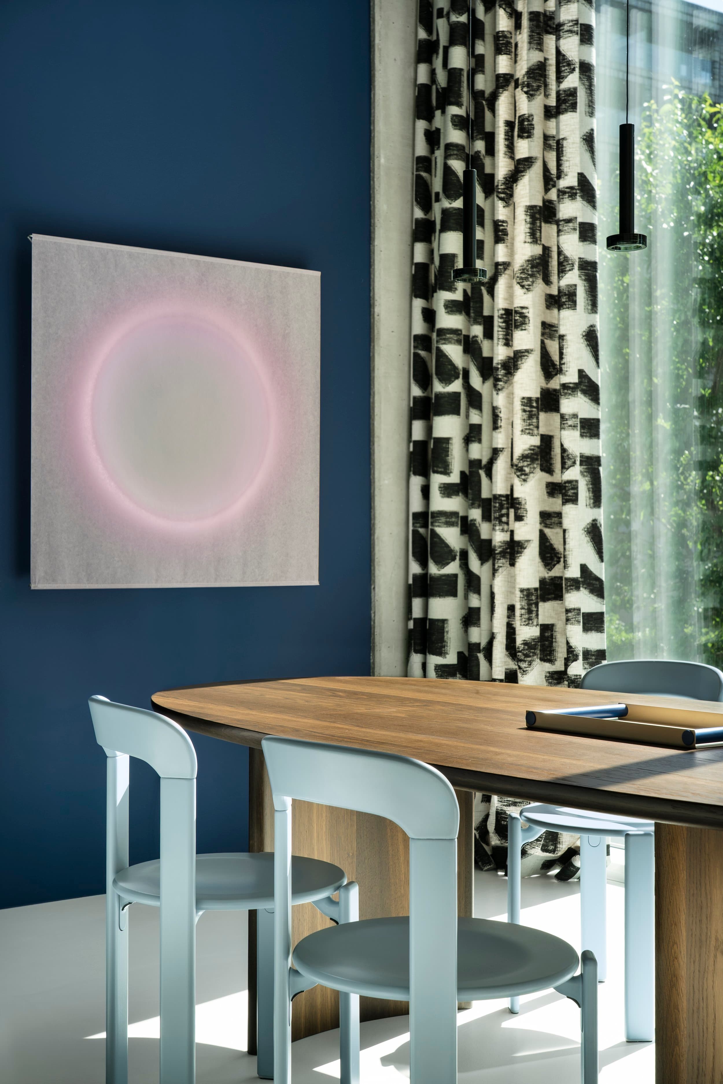 Interieurdetail met blauwe muur, houten tafel en lichte stoelen