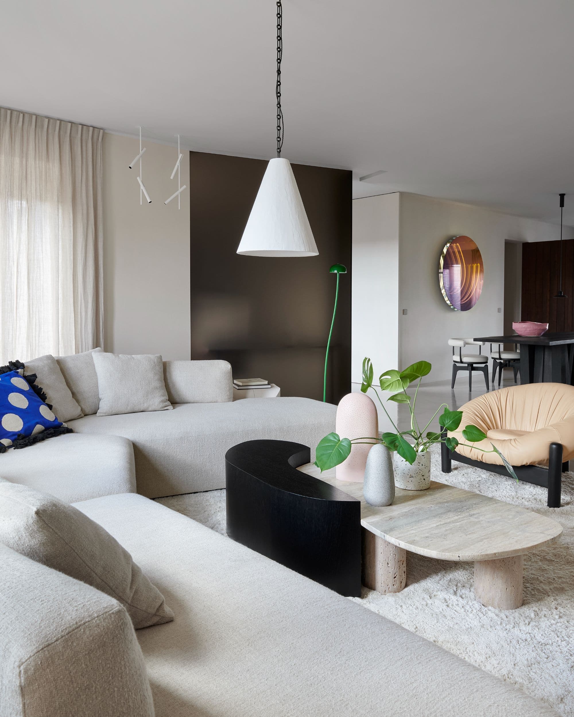 Woonkamer met beige hoekbank, zwarte salontafel en hangende lamp