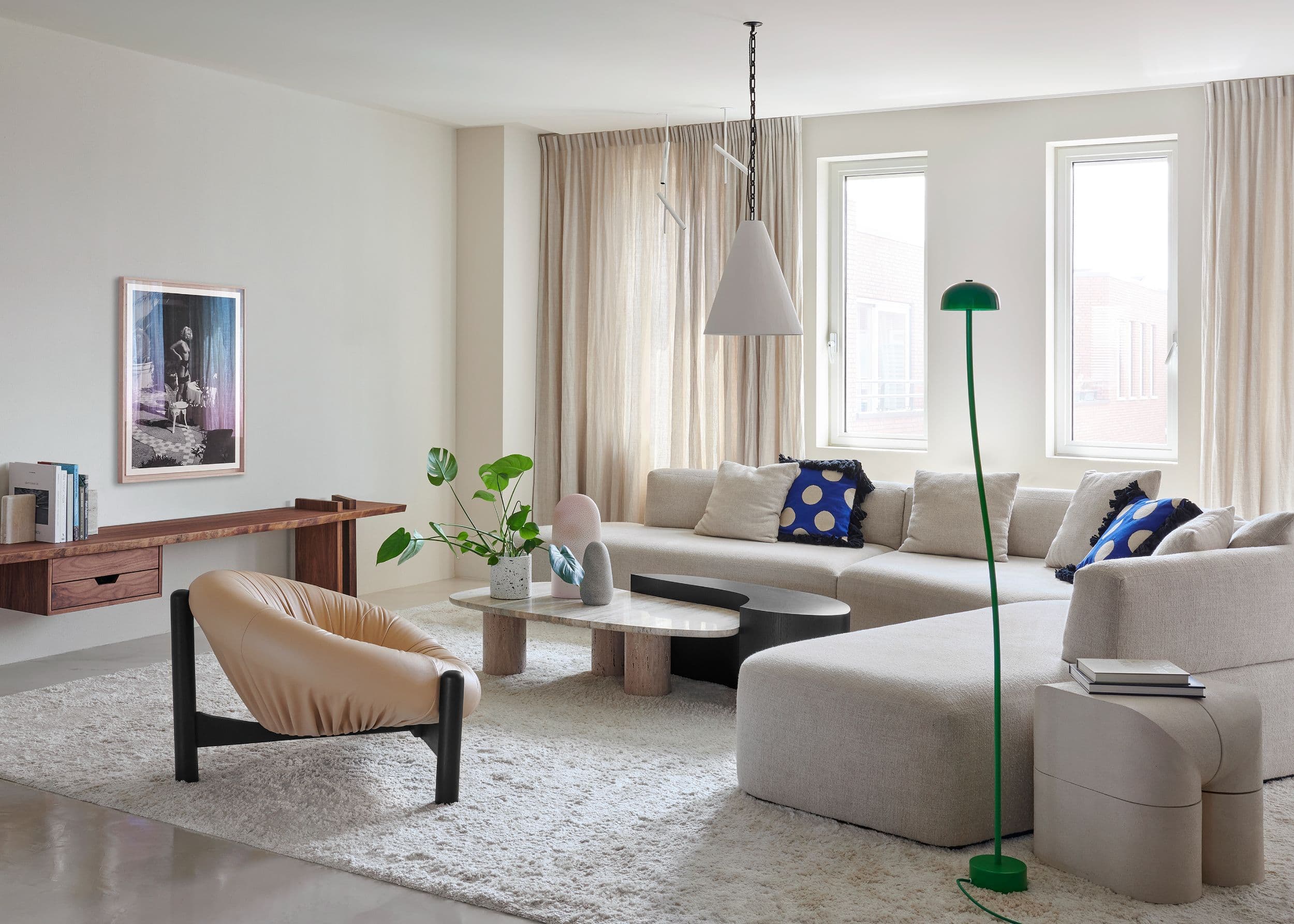 Woonkamer met beige hoekbank, houten dressoir en groene staanlamp