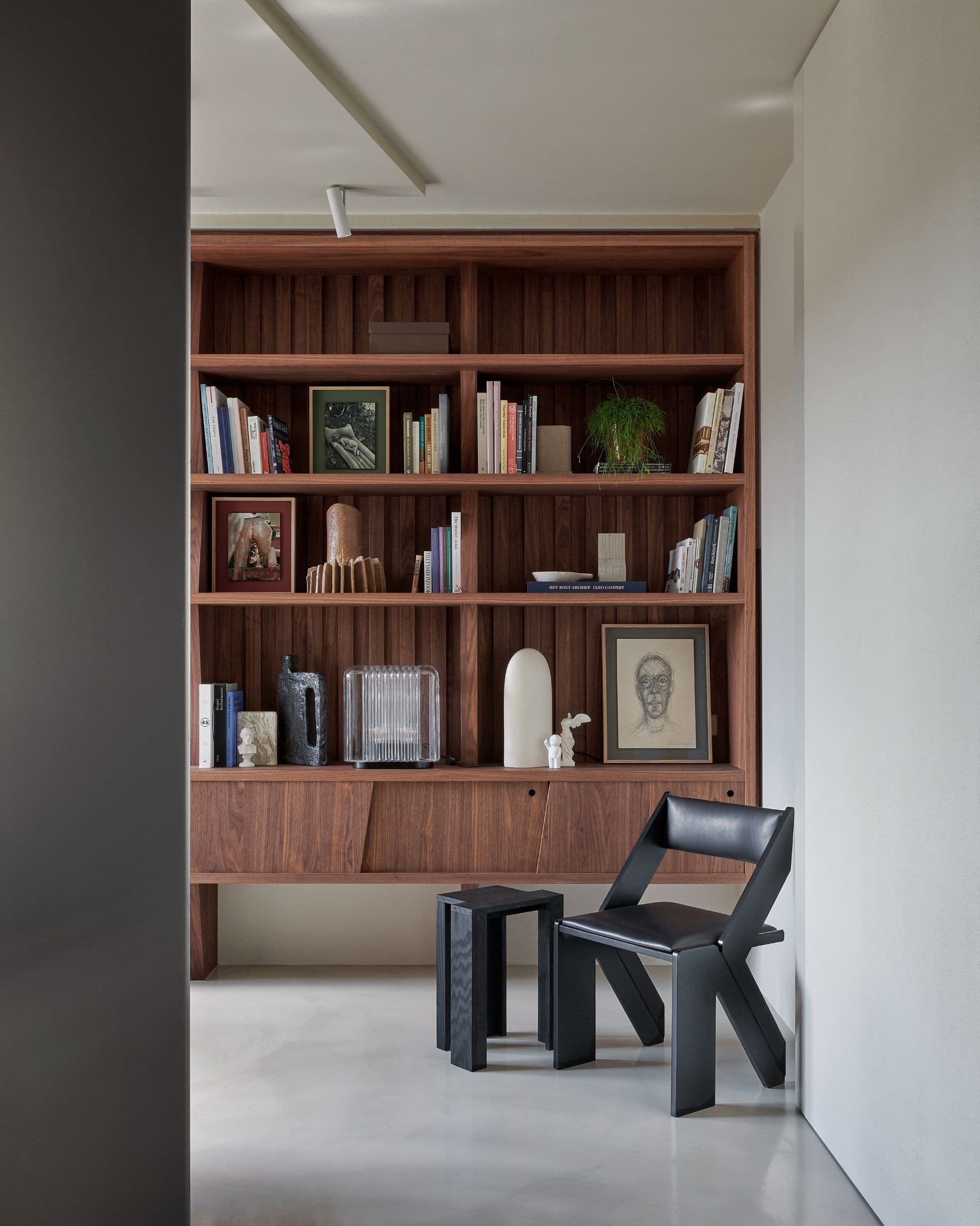 Boekenkasten met houten afwerking en zwarte design stoel