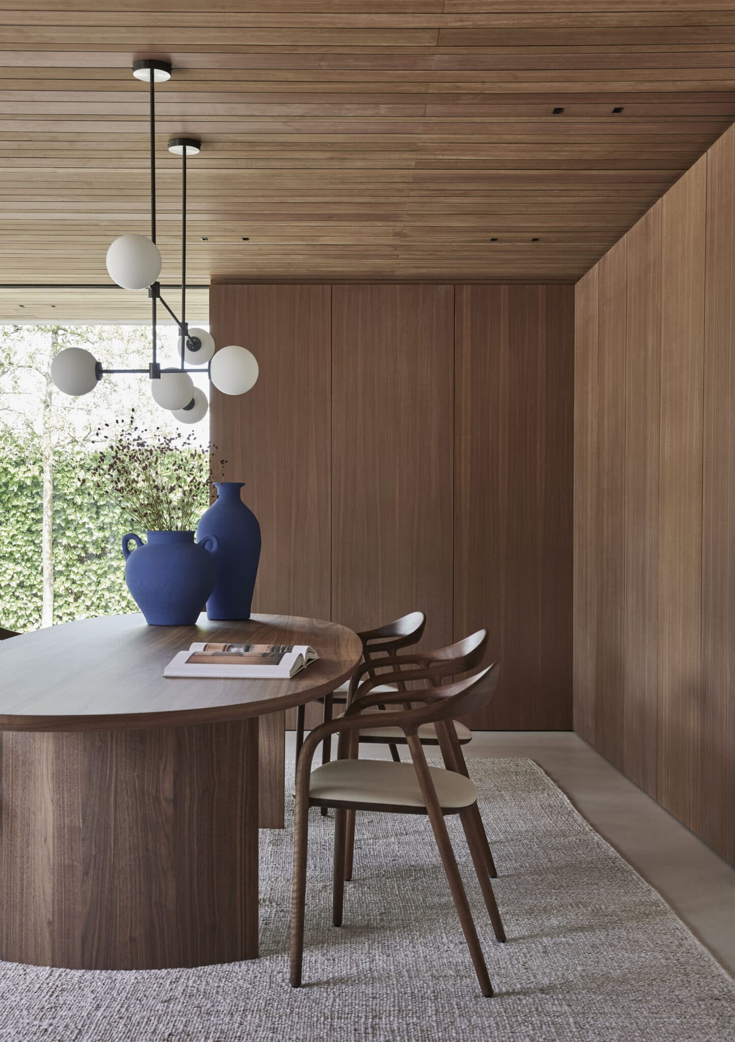 Terras met loungebanken onder boom en houten schermhek