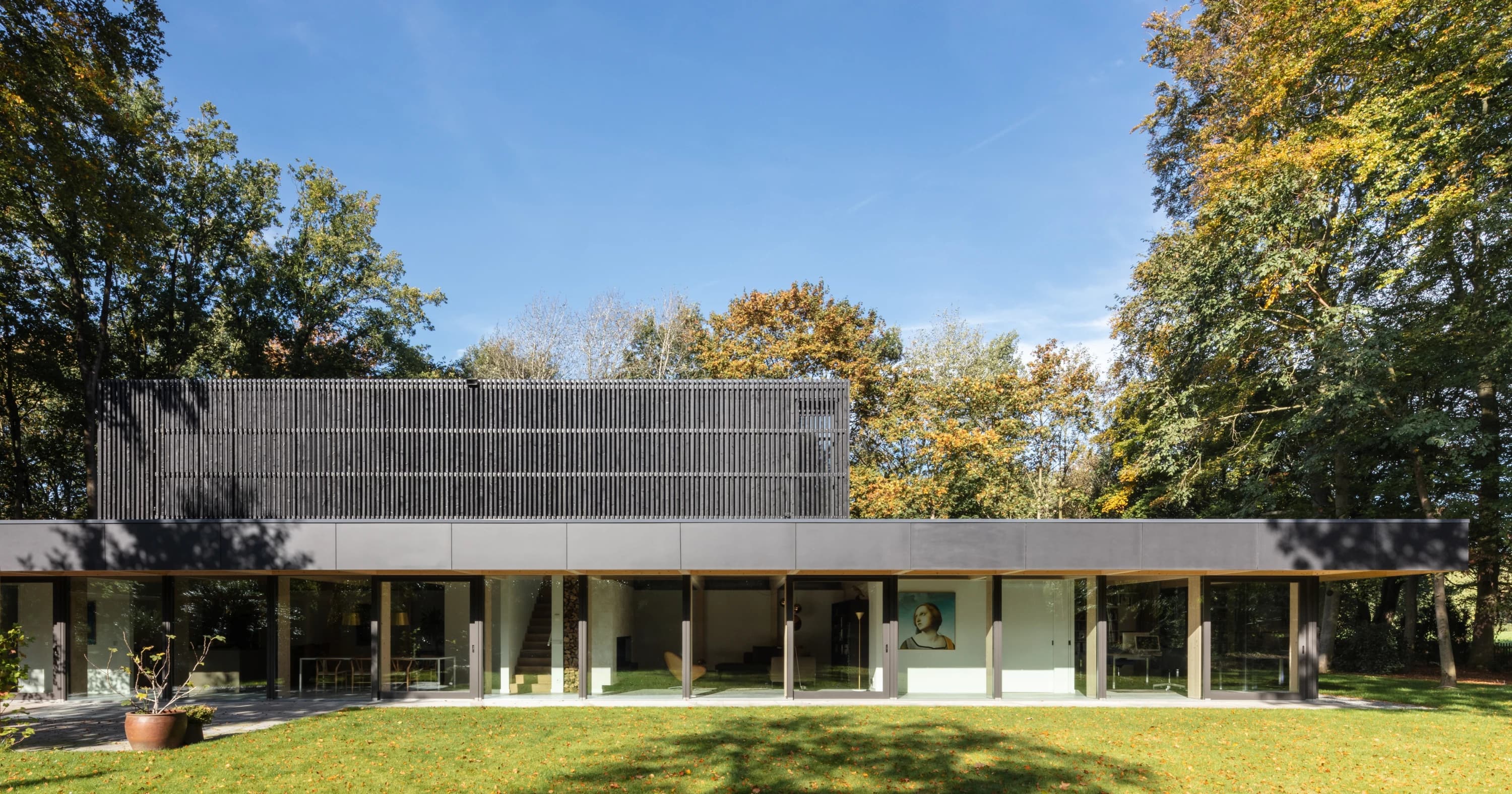 Moderne villa met houten palen, grote glazen ramen en zwarte bovenbouw