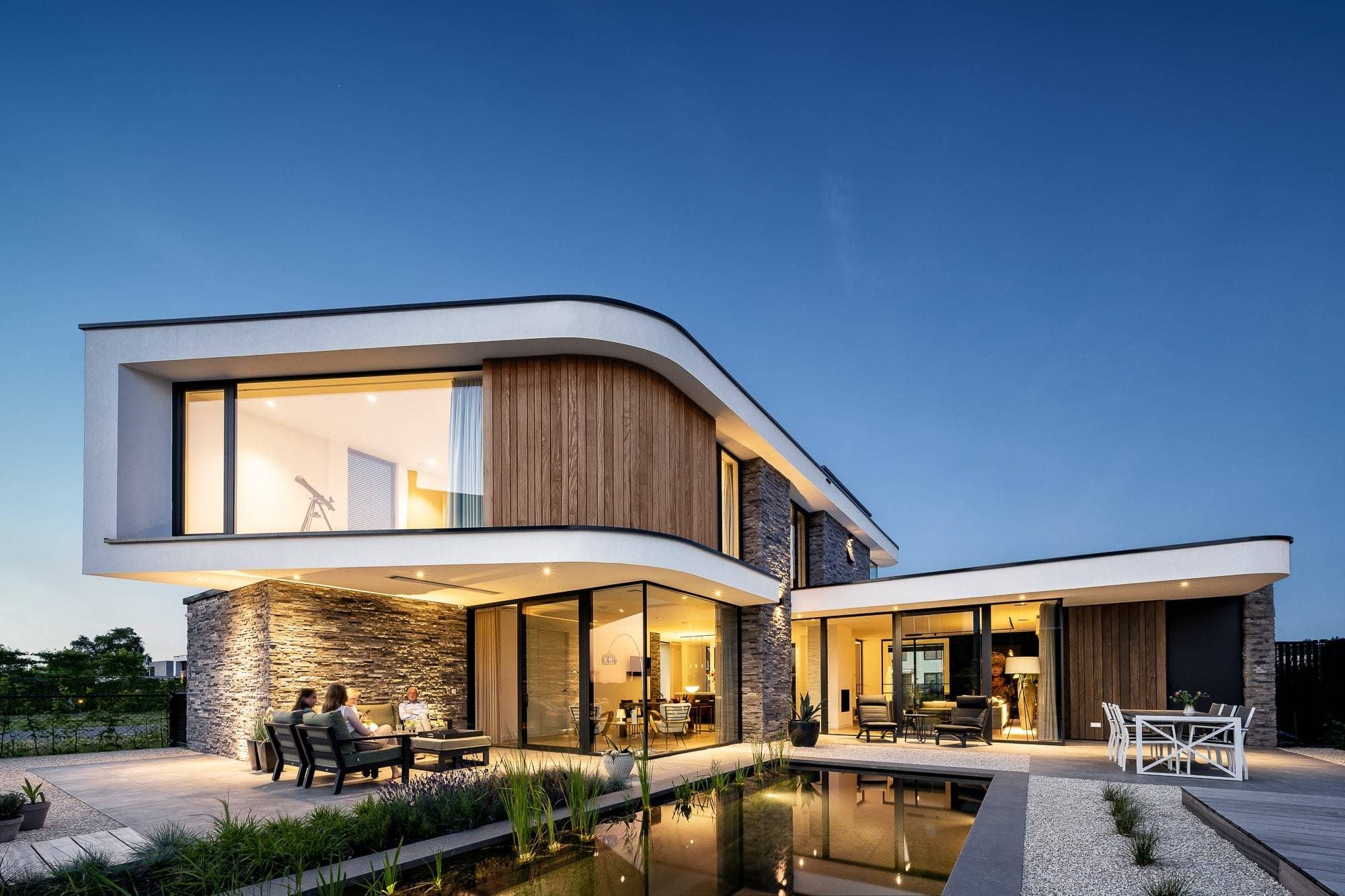 Voorgevel villa met gebogen witte gevel, houten bekleding en reflectievijver