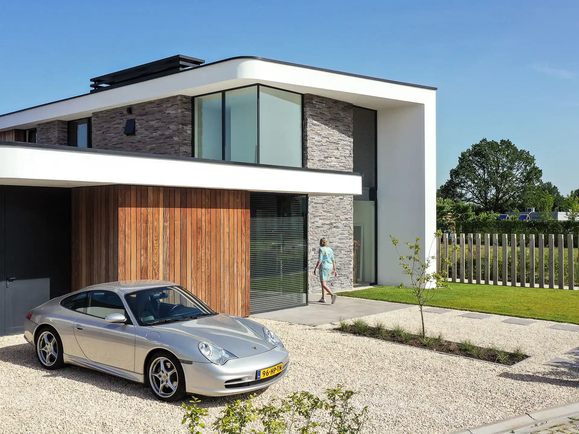 Hoek voorgevel met grijze natuurstenen wand, wit betonwerk en grote glazen elementen