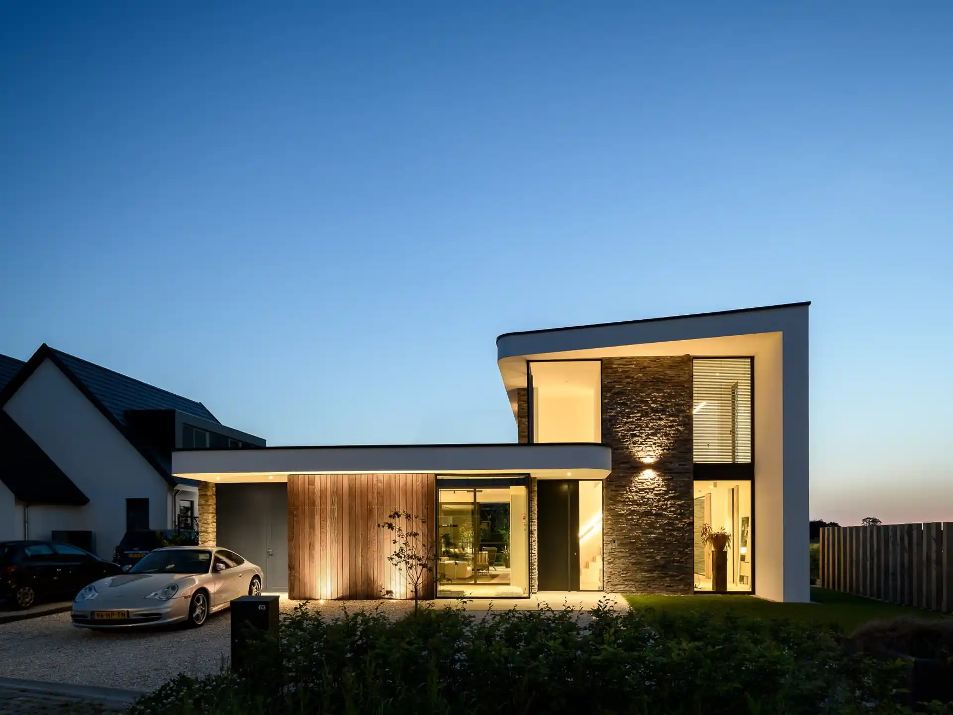 Zijgevel moderne villa met stenen sokkel, houten lamellen en carport