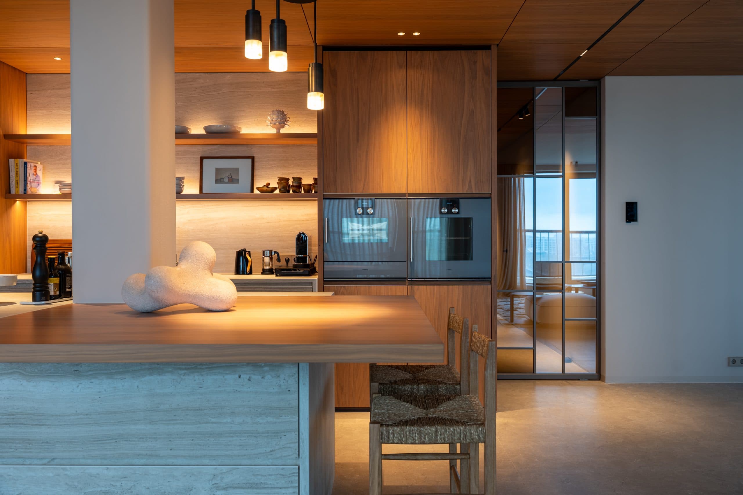Open keuken met houten kastenwand en wit keukeneiland met houtfineer