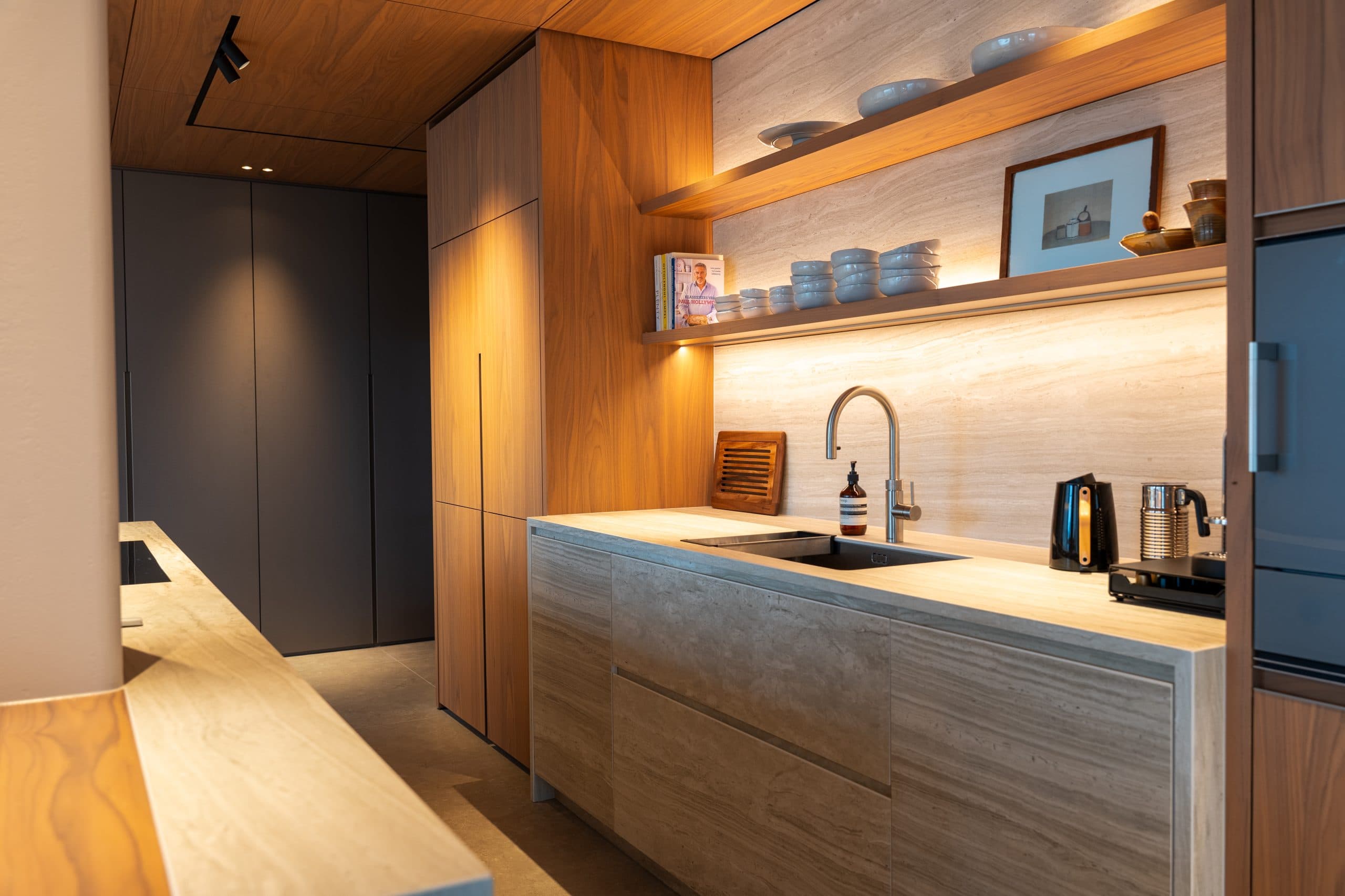 Kitchenette met grijze kasten, houten accenten en verlichte wandplanken