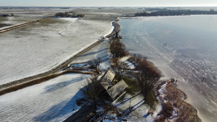 Luchtfoto waterland met dijk, bomen en geïsoleerde woning