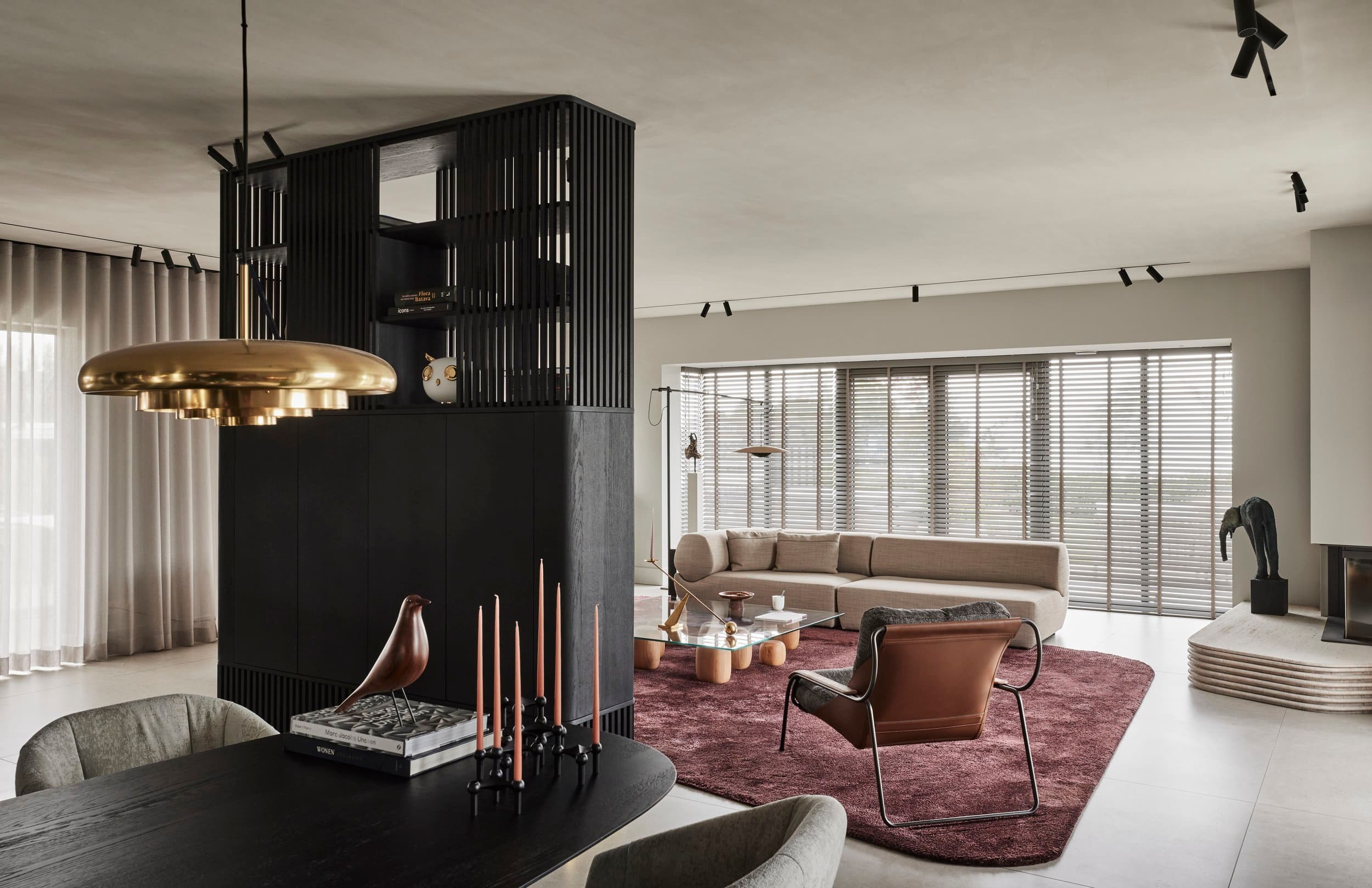 Open woonkamer met haard, beige bank en aubergine vloerkleed