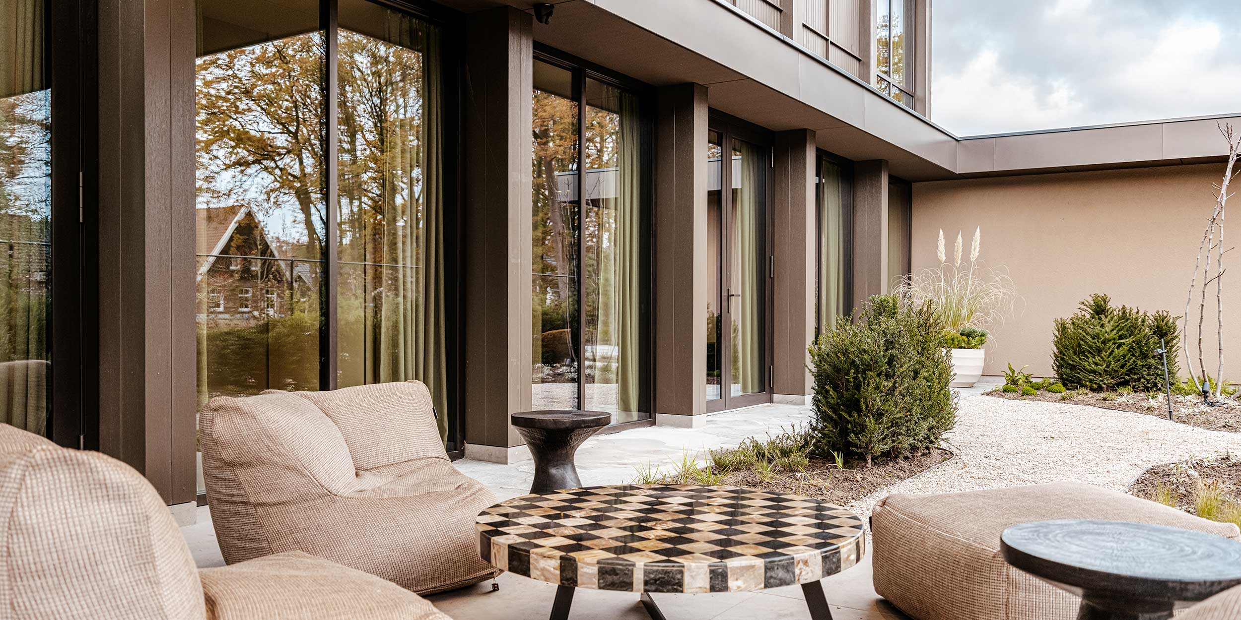 Terrashoek met beige linnen loungemeubels en grote schuiframen