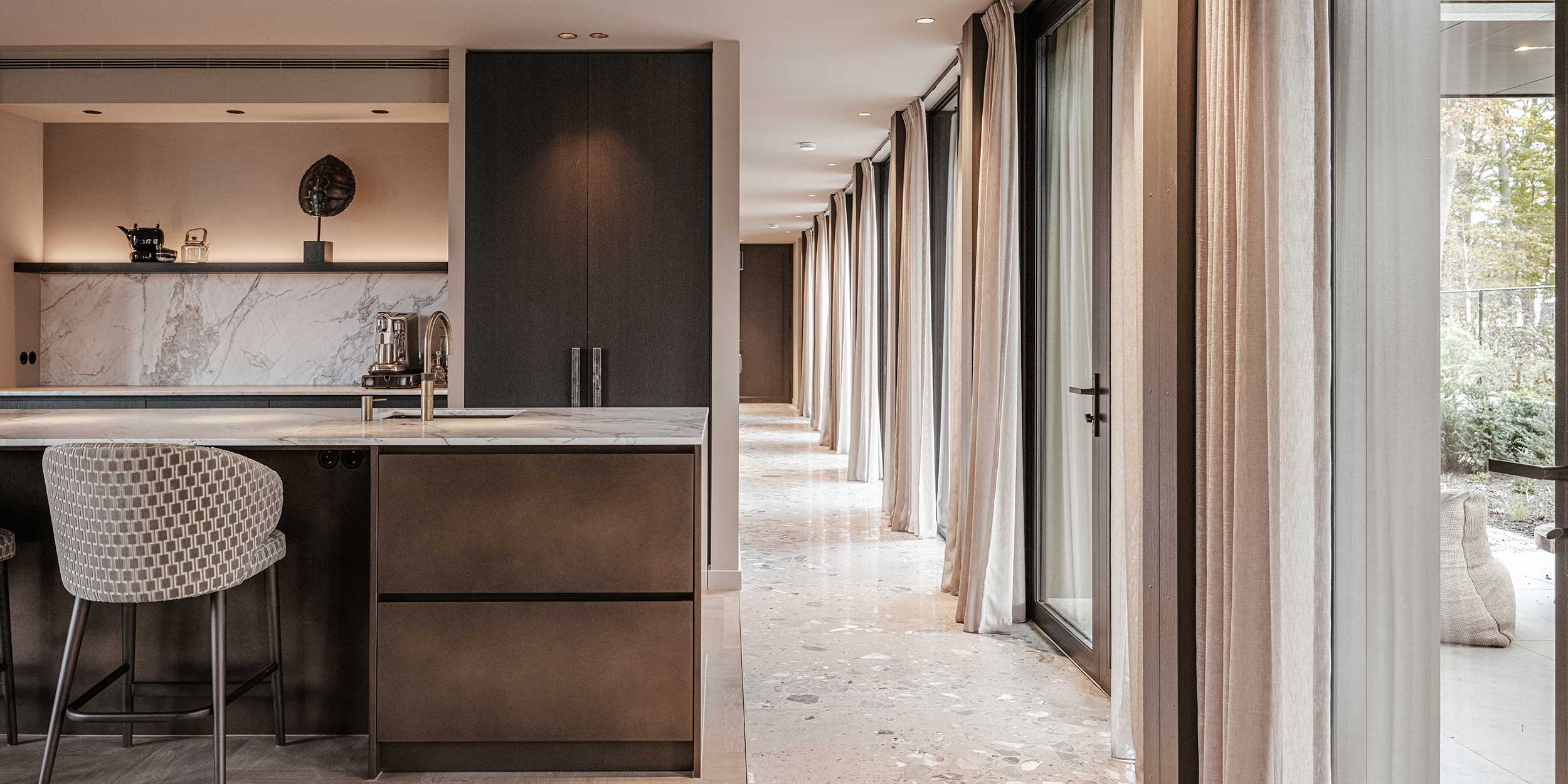 Keuken met donkerbruine kasten en marmeren werkblad, zicht op corridor