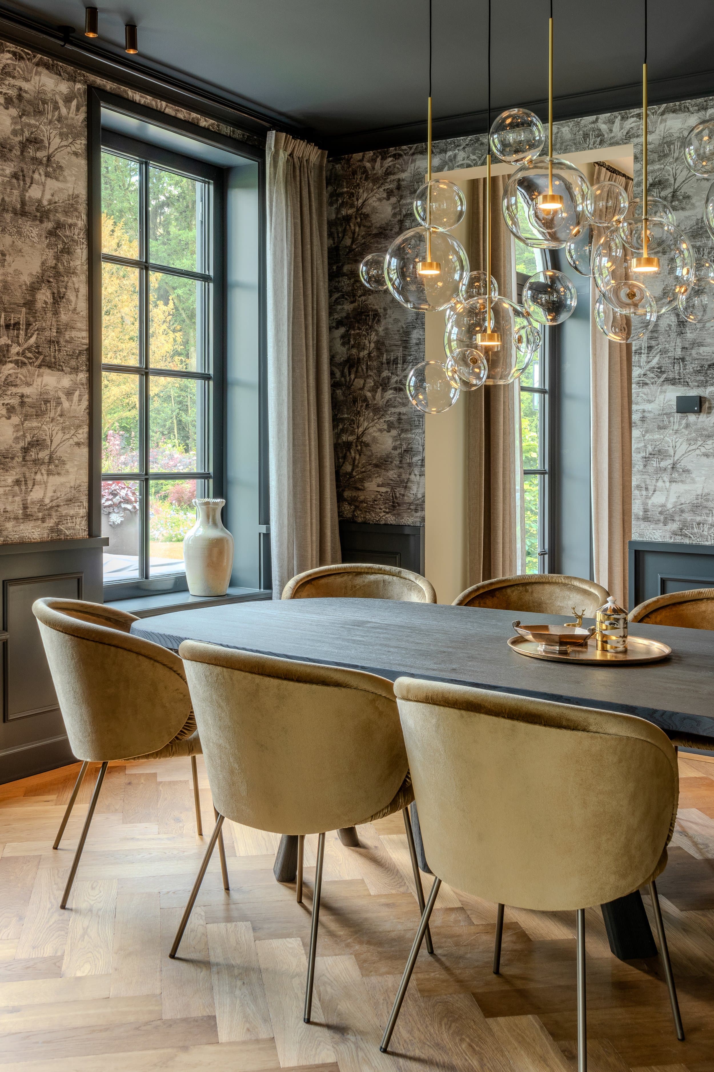 Elegant dining space with patterned wallpaper, glass pendants and large windows