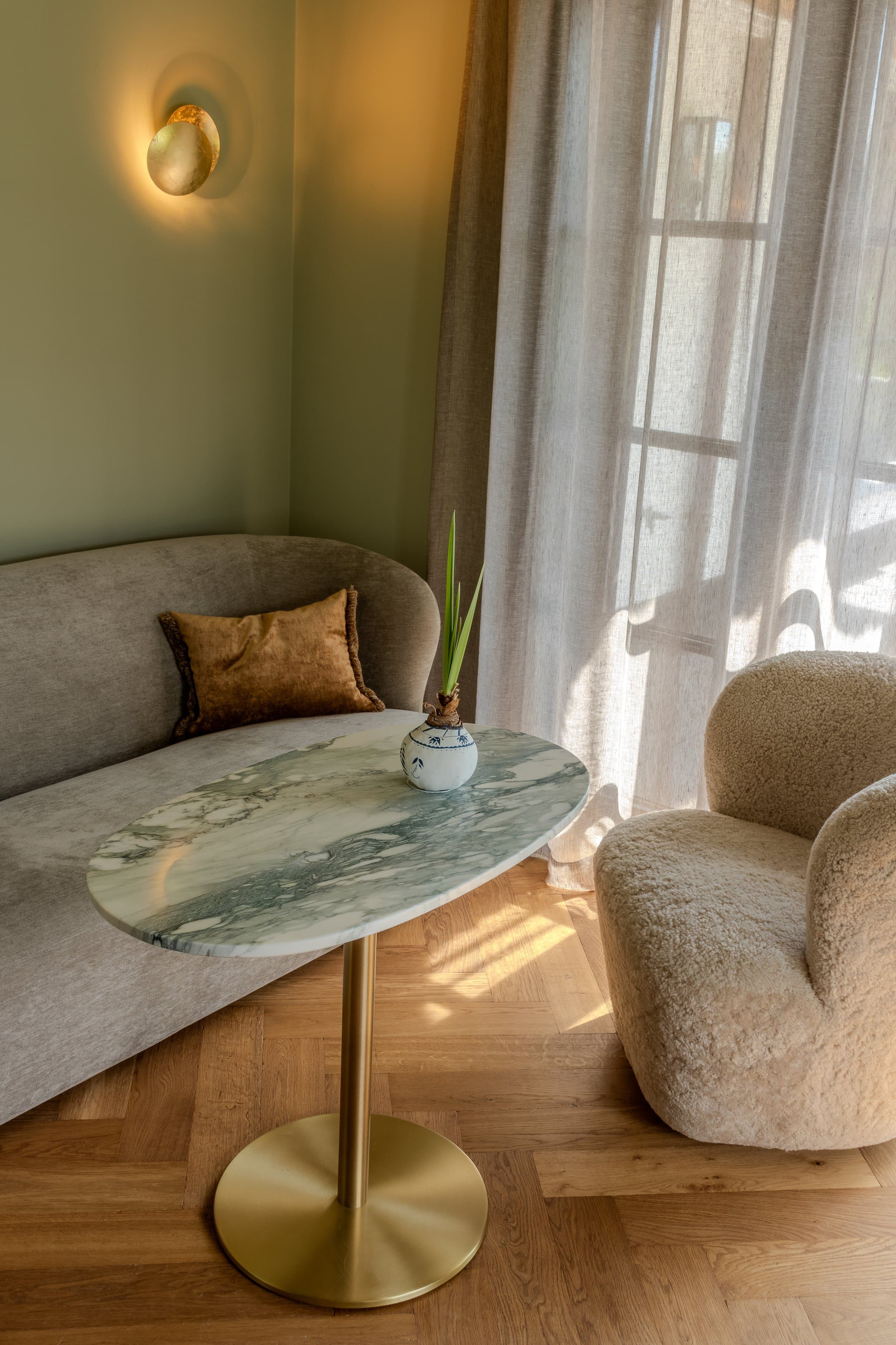 Minimalist seating nook with pale sofa, marble table and soft lighting