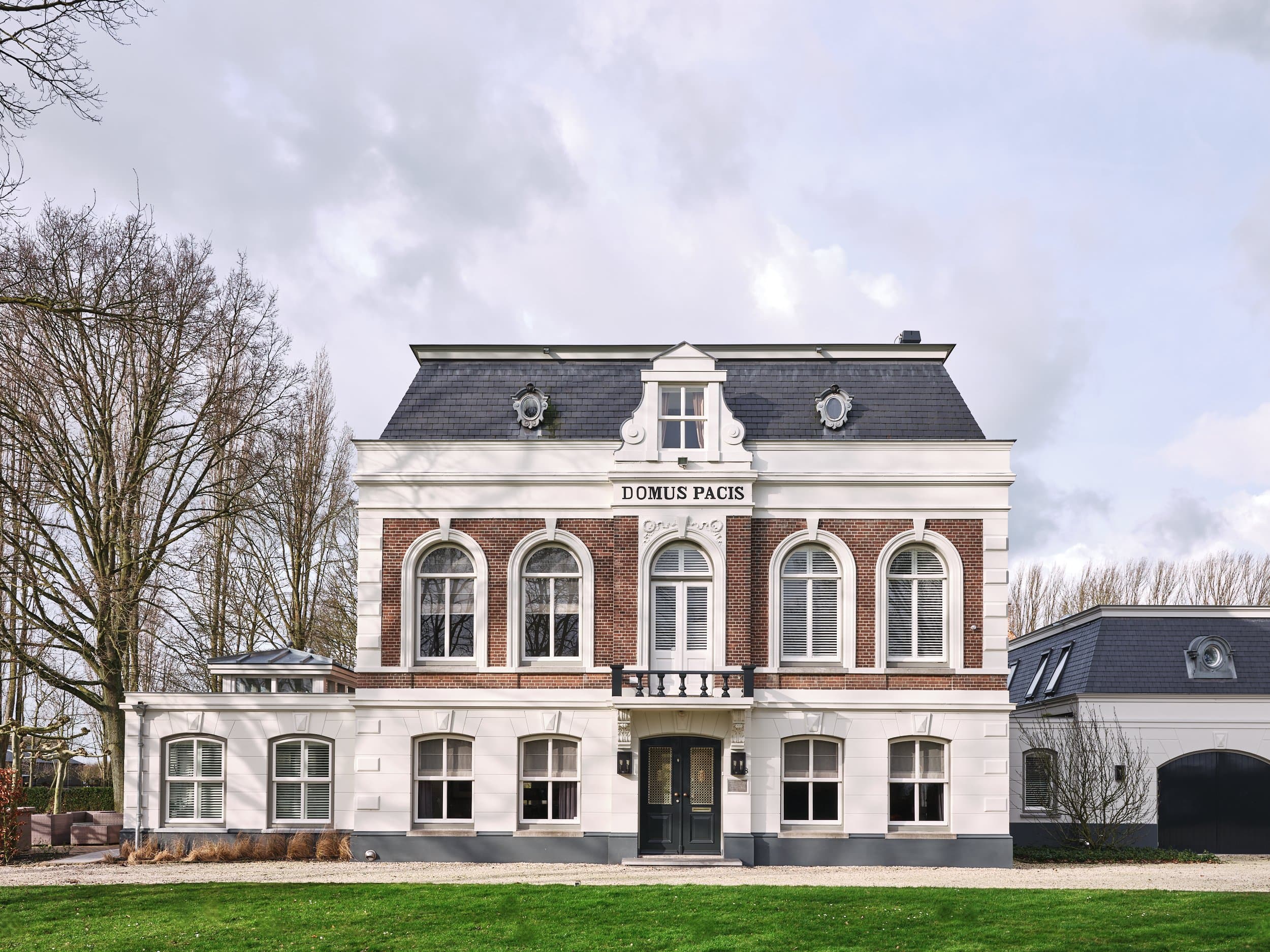 Neoclassicistische villa met rode baksteen, witte stucwerk en mansardedak