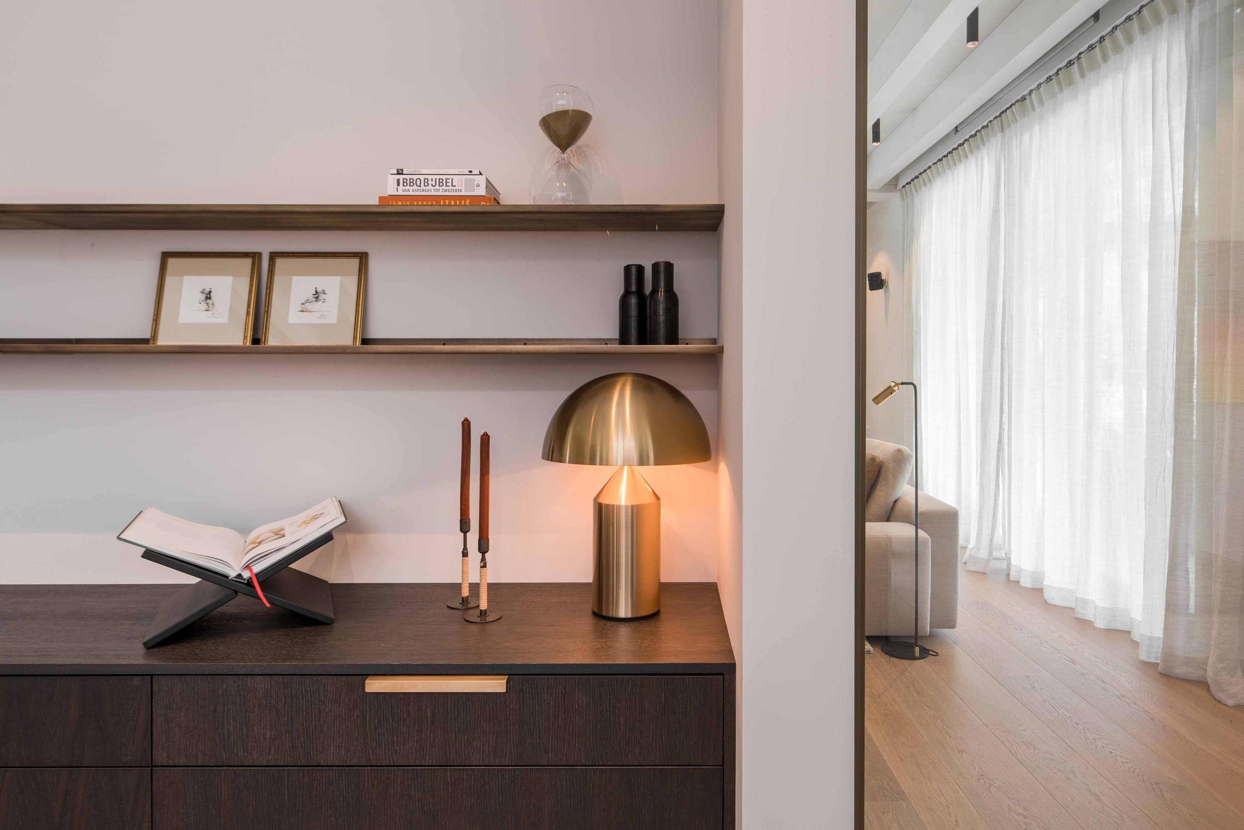 Werkkamer met roze muren, donker houten bureau en metalen bureaulamp