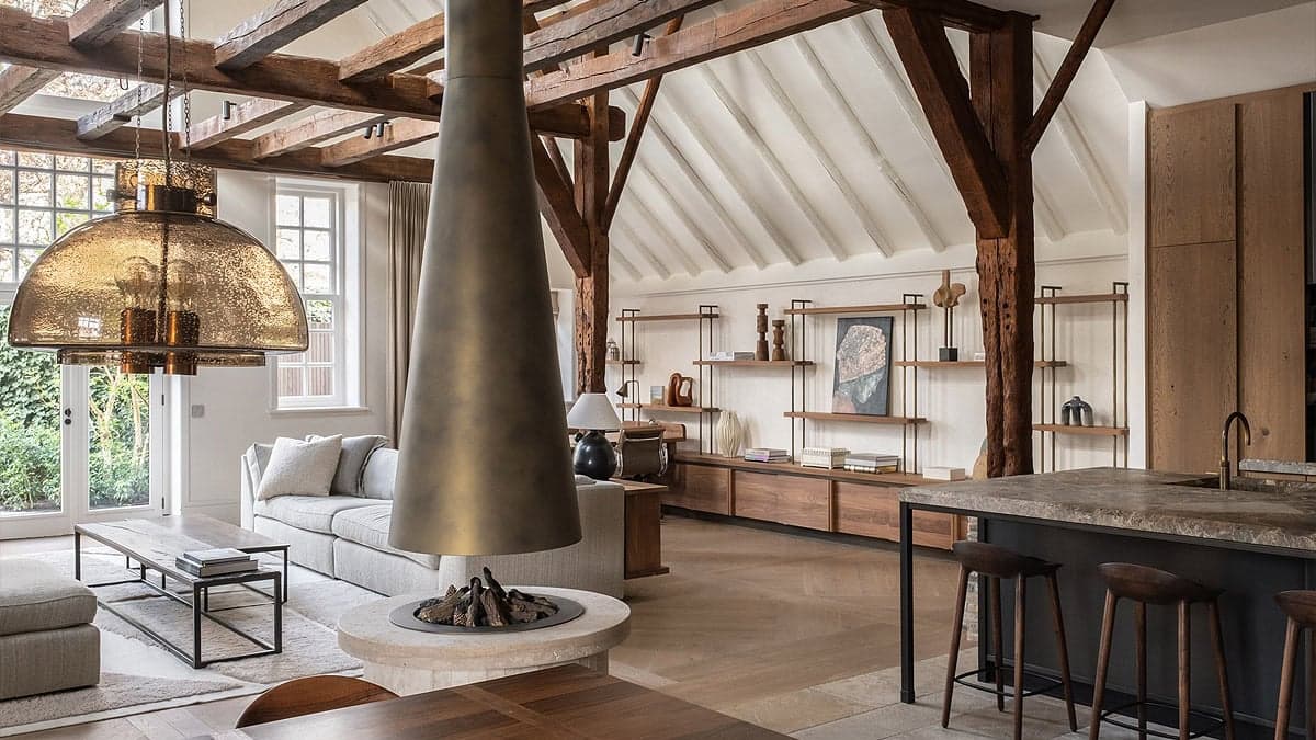 Woonkamer met houten balkenstructuur, kegelvormige hangerlamp en open haard