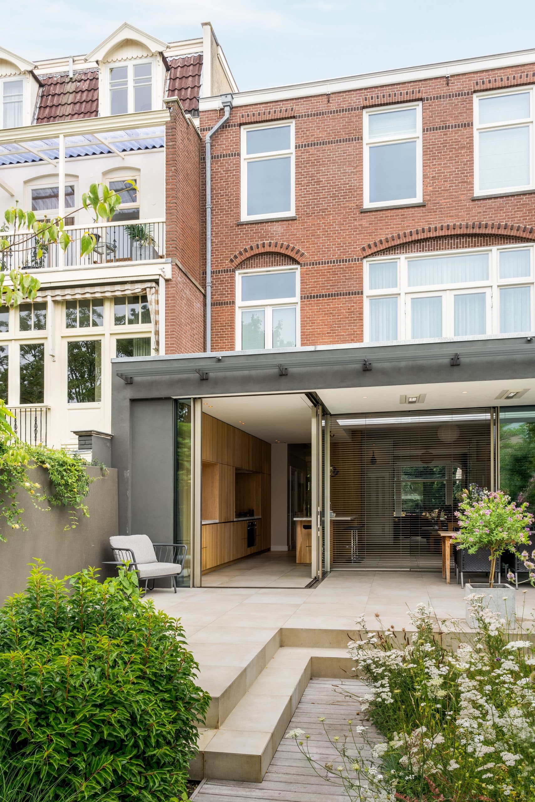 Garage in rode baksteen met zwarte deuren en kunstwerk op gevel