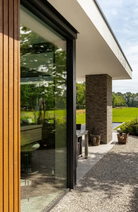 Detalieramen en houten deurkozijn tegen bakstenen villa-gevel