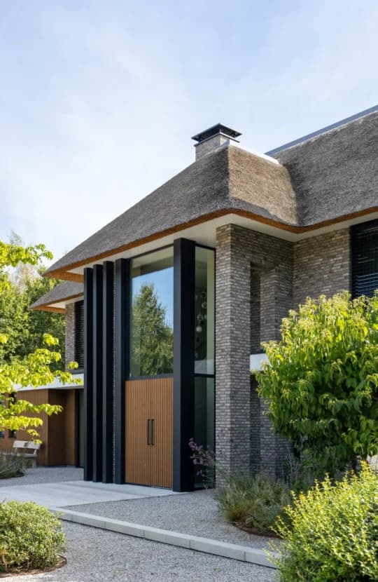 Detail ingang met rietgedekt dak, baksteengevel en houten deur