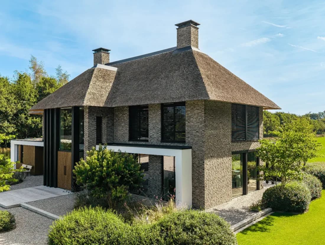 Ronde bakstenen villa op twee verdiepingen met rietdak