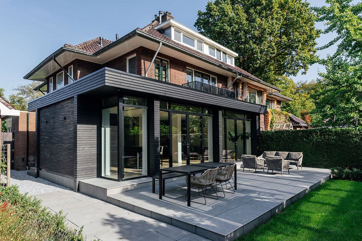 Moderne uitbouw met donkergrijze houten gevel en grote glasvlakken