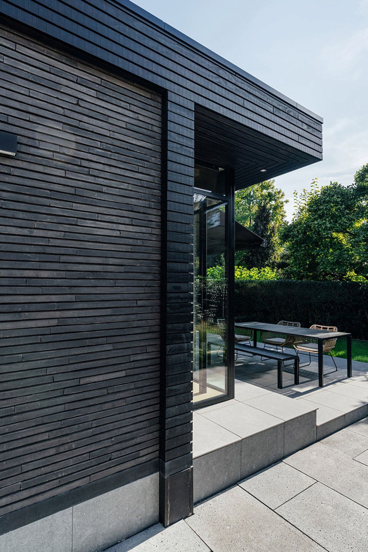Detail grote glazen schuifdeuren met zwart stalen frame op terras