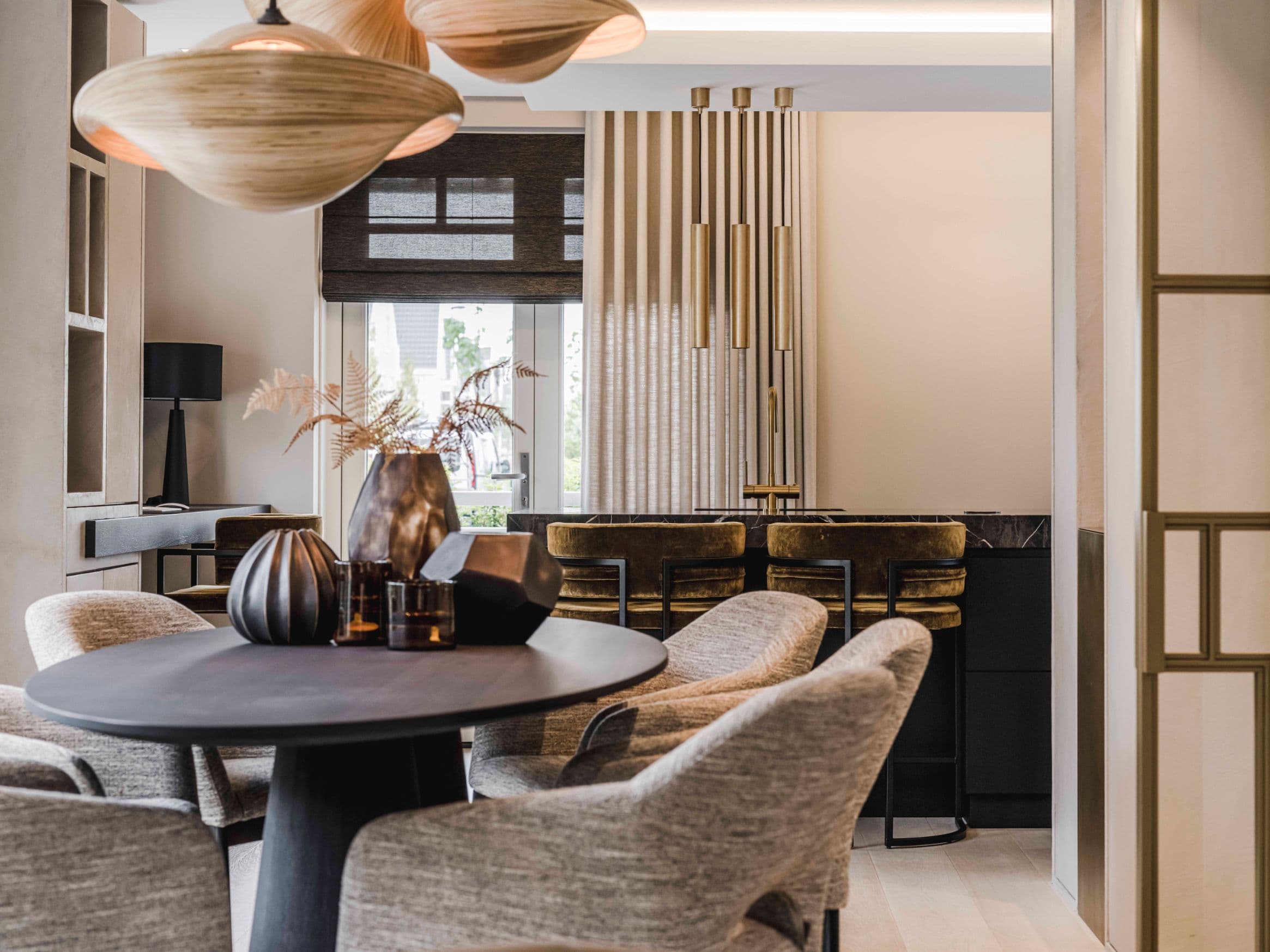 Eetkamer met zwart rond tafel, grijze stoelen en houten hangende lampen
