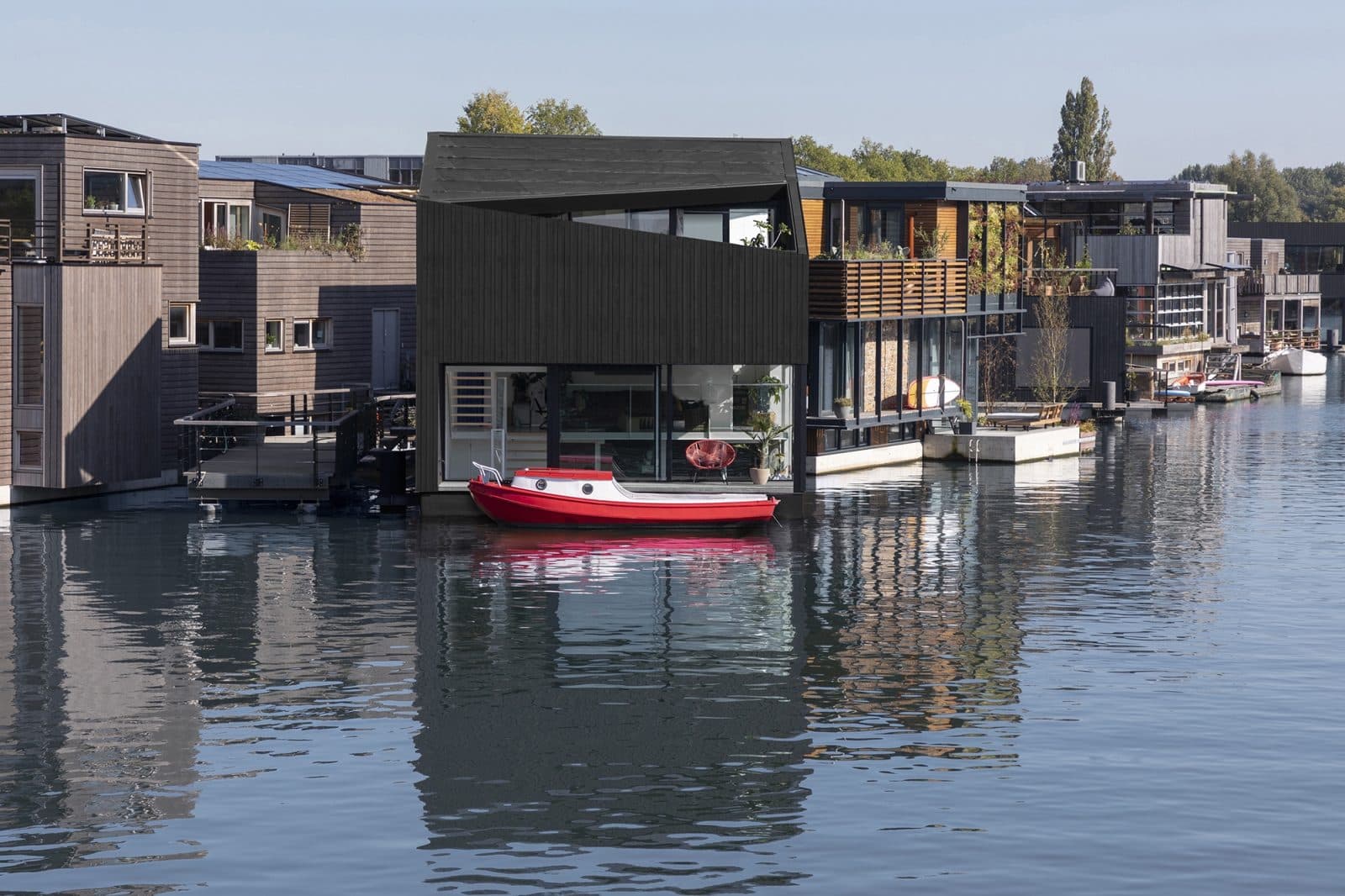 Rij moderne woningen aan water met zwarte houten gevels